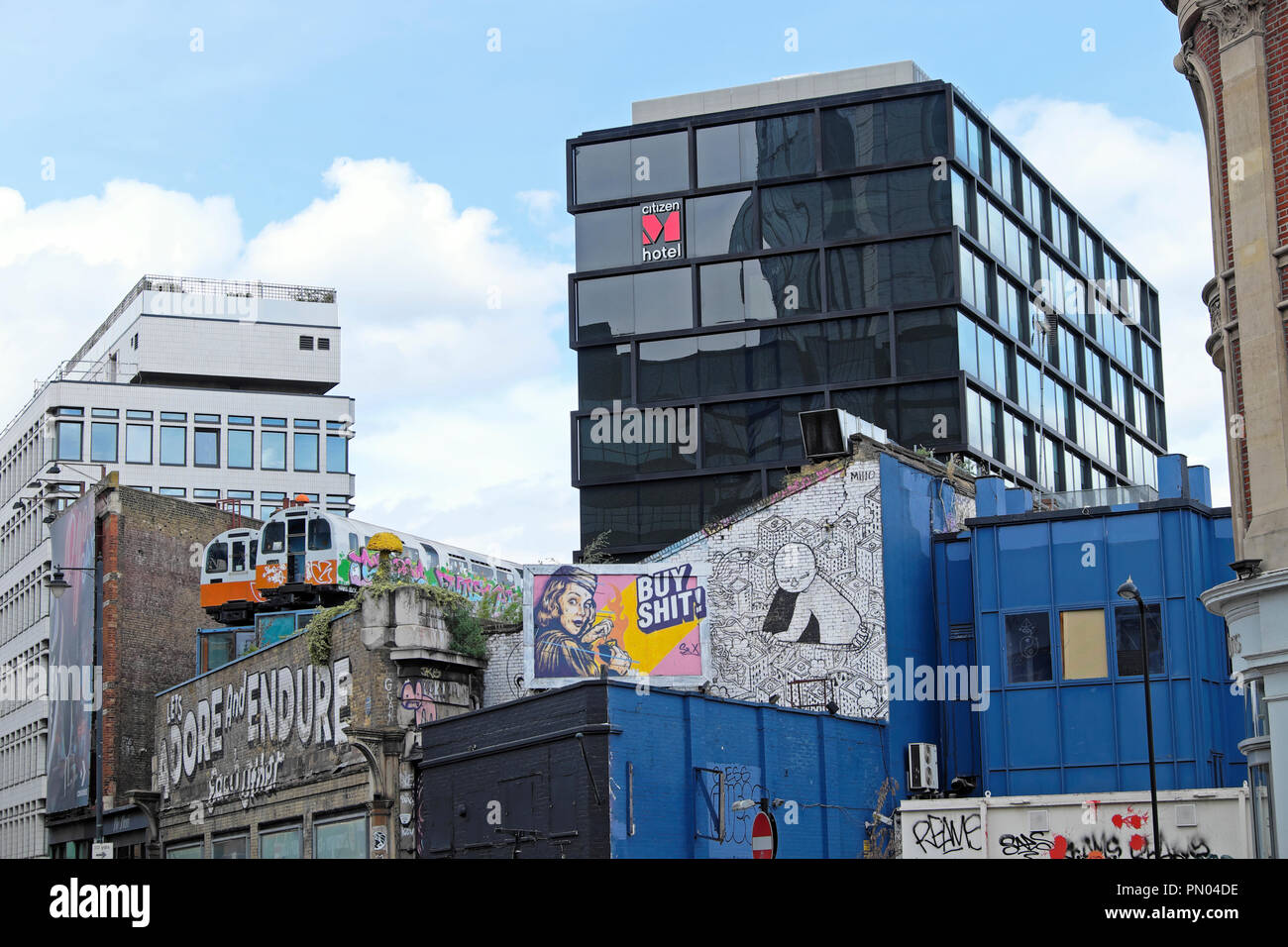 'Laßt uns anbeten und Ertragen, Einander "Graffiti an der Wand mit Waggons auf dem Dach Great Eastern Street Art in Shoreditch East London UK KATHY DEWITT Stockfoto