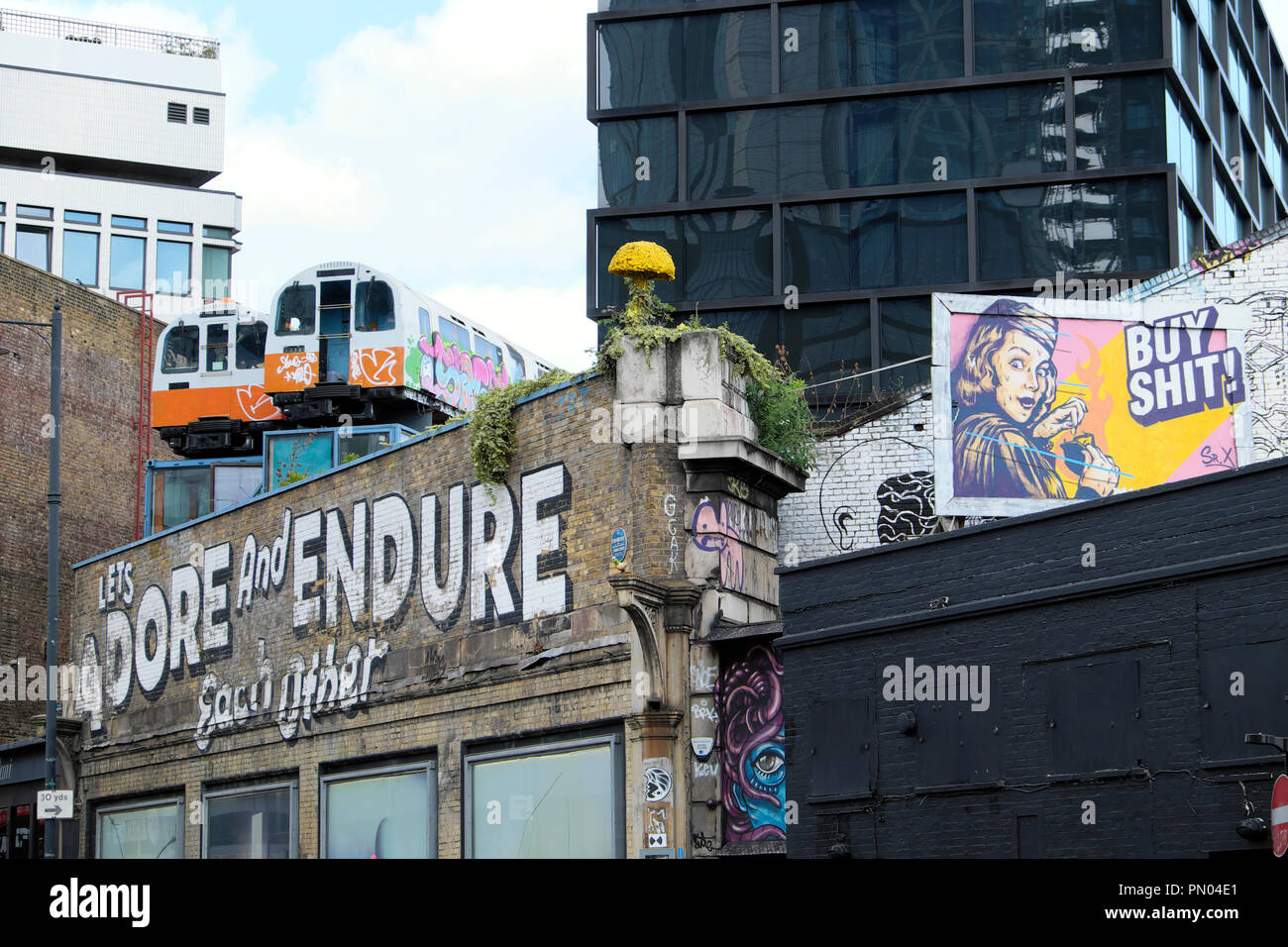 'Laßt uns anbeten und Ertragen, Einander "Graffiti an der Wand mit Waggons auf dem Dach Great Eastern Street Art in Shoreditch East London UK KATHY DEWITT Stockfoto