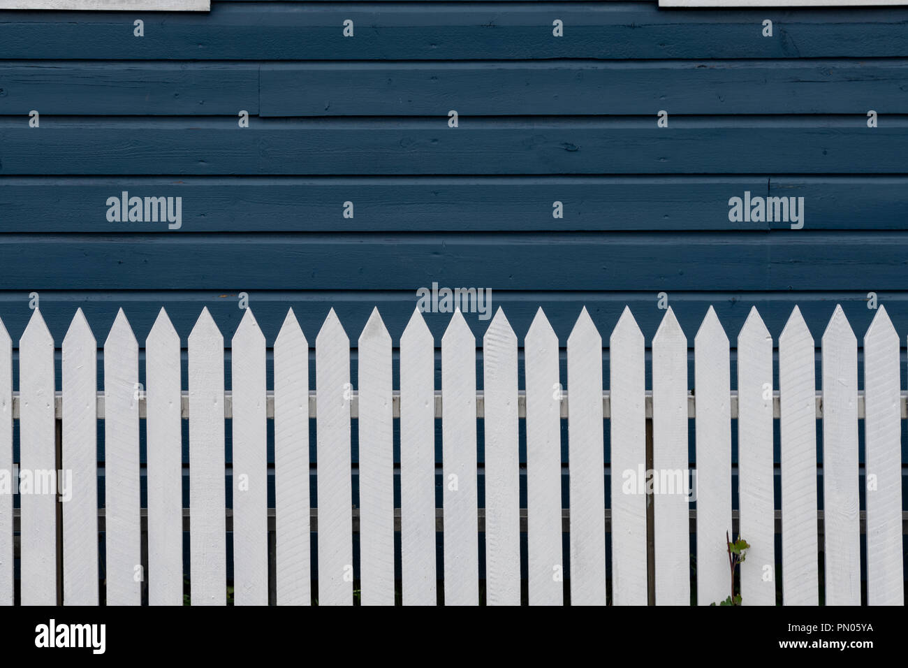 Weißen lattenzaun vor Rick blau Wetter verschalte Haus gemalt. Als Hintergrundbild nützlich Stockfoto
