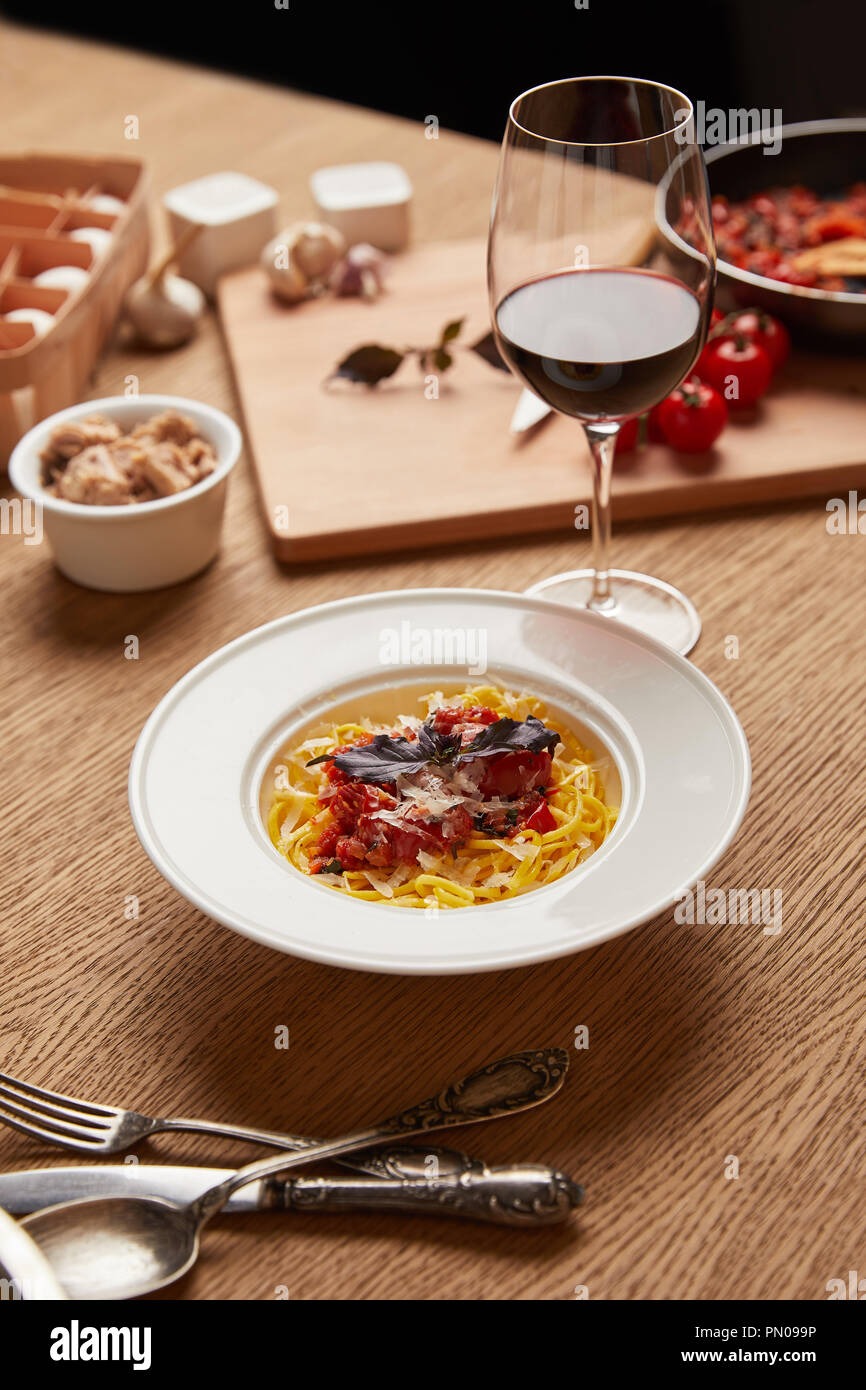Teller köstliche Pasta mit verschiedenen Zutaten und Wein rund um auf hölzernen Tisch Stockfoto