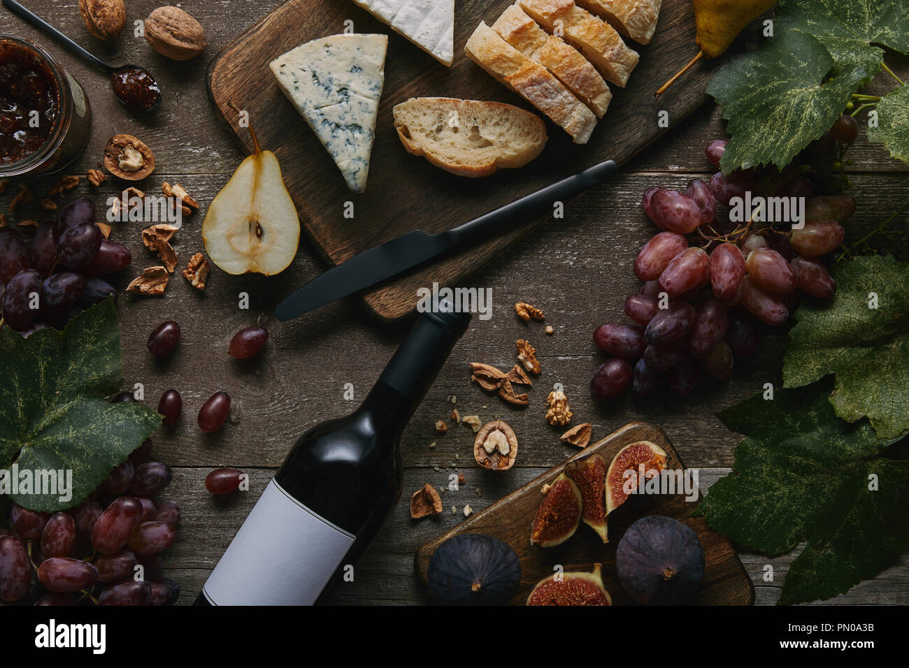 Blick von oben auf die Weinflasche mit leeren Etikett, frisches Obst und leckere Snacks auf hölzernen Tisch Stockfoto