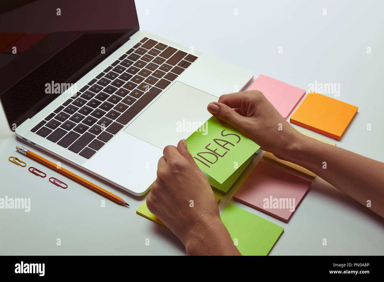 Zugeschnittenes Bild der Frau mit Hinweis Papier mit Wort Ideen in der Nähe von Laptop Stockfoto