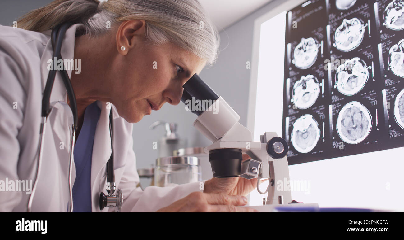 Im mittleren Alter Neurologe weibliche Untersuchung mit Mikroskop Stockfoto