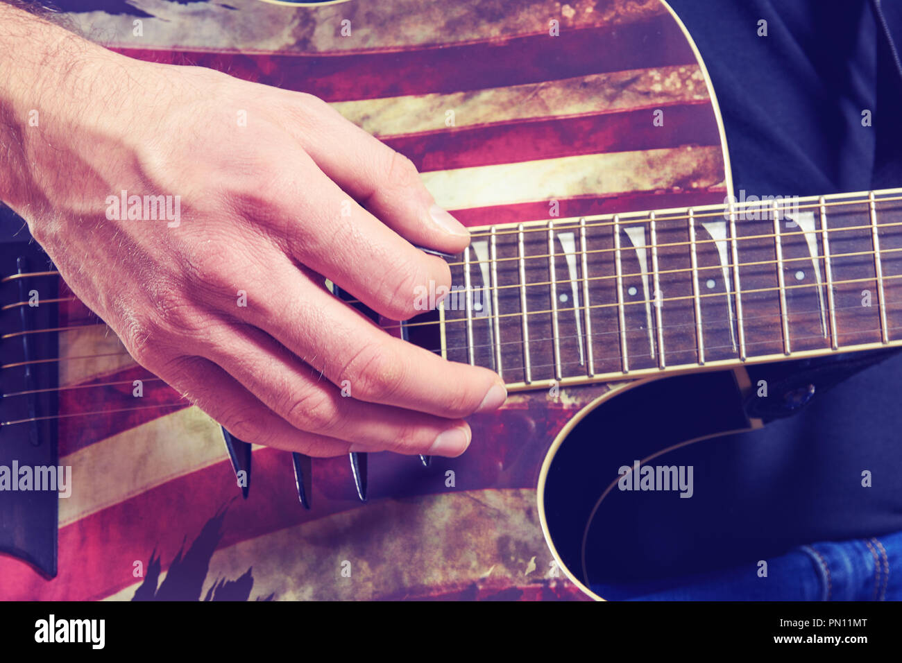 Der Mann in einem schwarzen T-Shirt und Jeans spielt eine akustische Gitarre. Finger detail Stockfoto