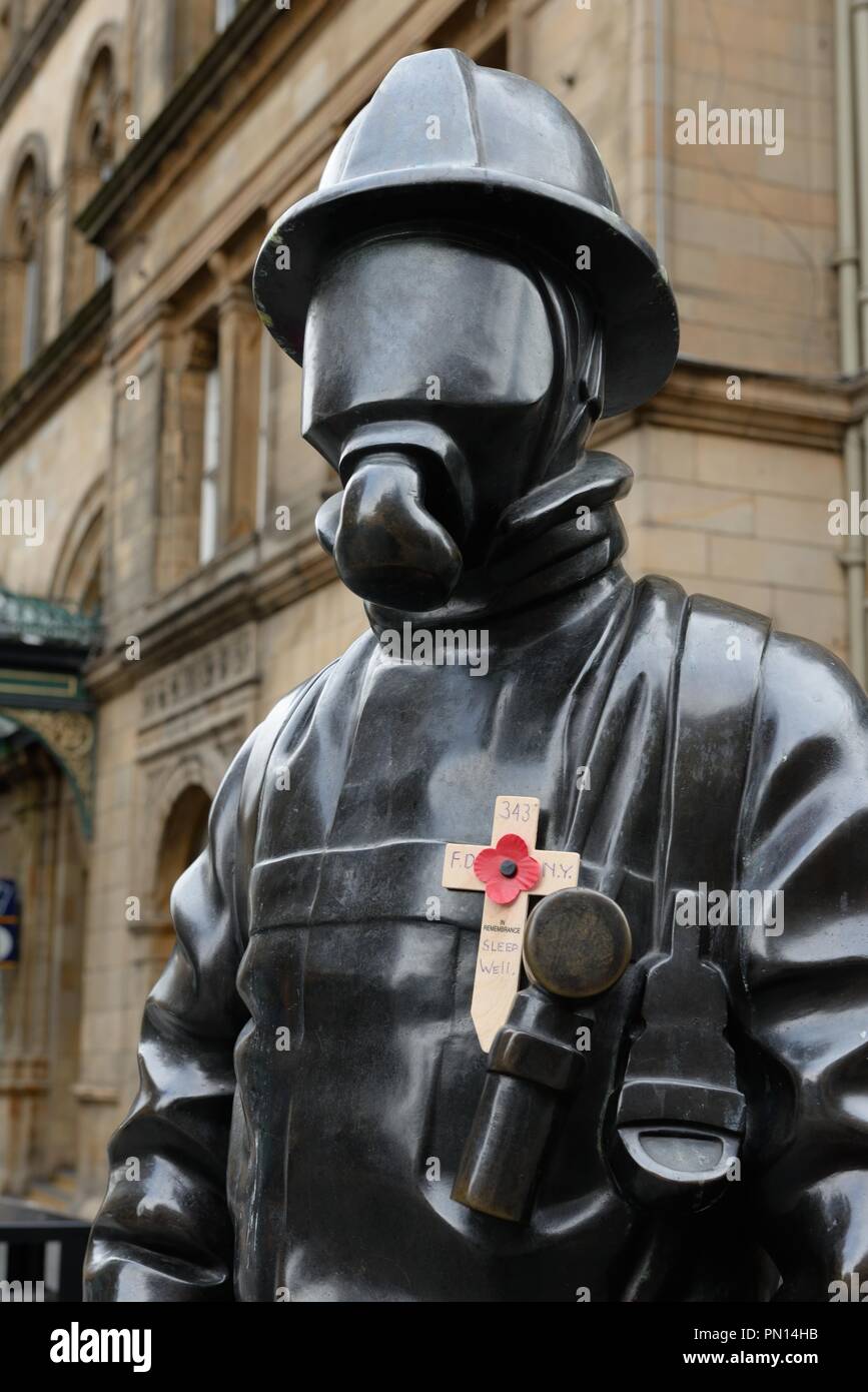 Die Bürger Feuerwehrmann bronze Tribut Statue mit einem hölzernen Kreuz und Poppy Hingabe an die 911 Todesopfer Glasgow, Schottland, Großbritannien geschmückt. Stockfoto
