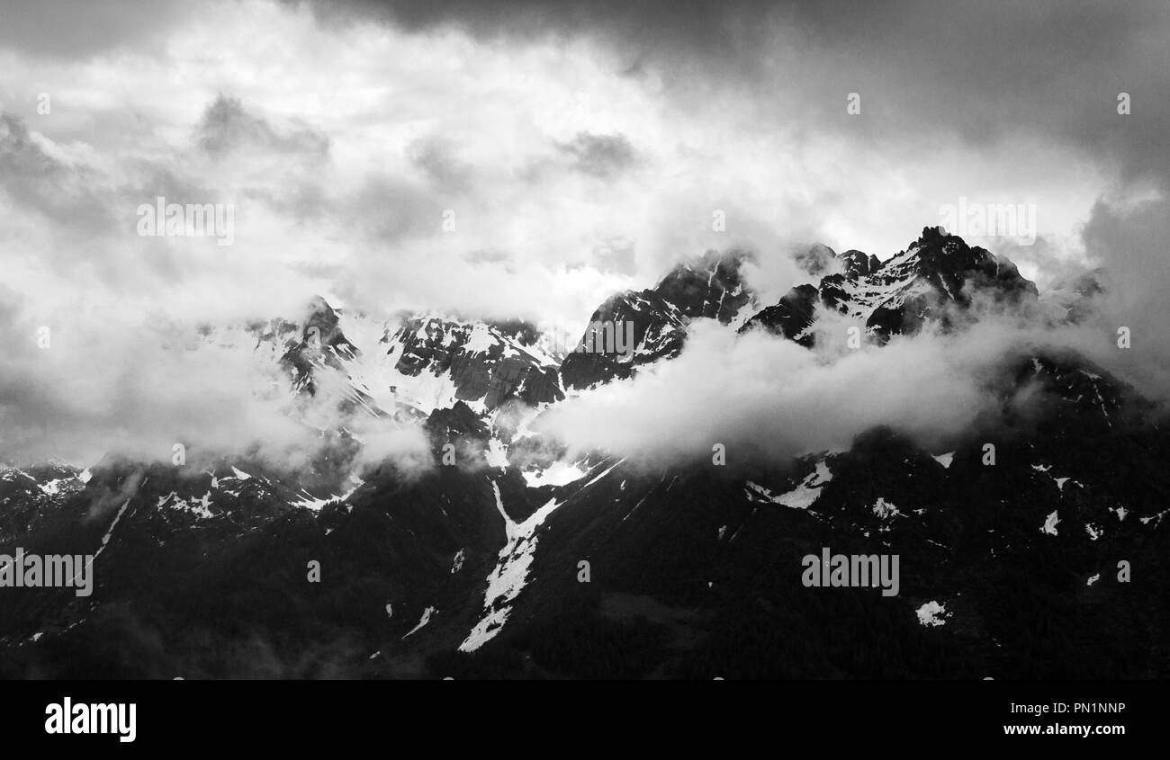 Monochrome eines schneebedeckten Bergkette von Wolken bedeckt. Stockfoto