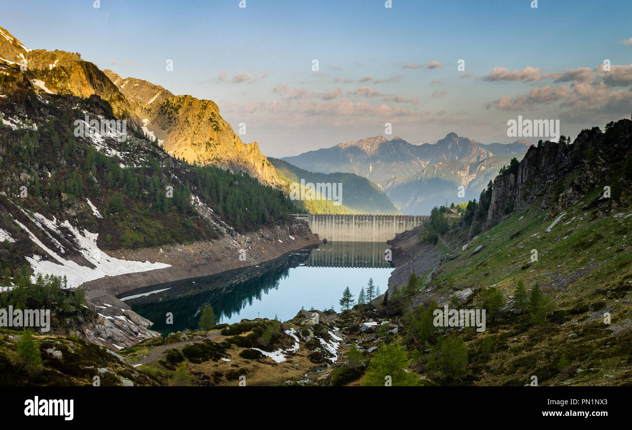 Ein Staudamm und ein See in den Bergen bei Sonnenaufgang. Stockfoto