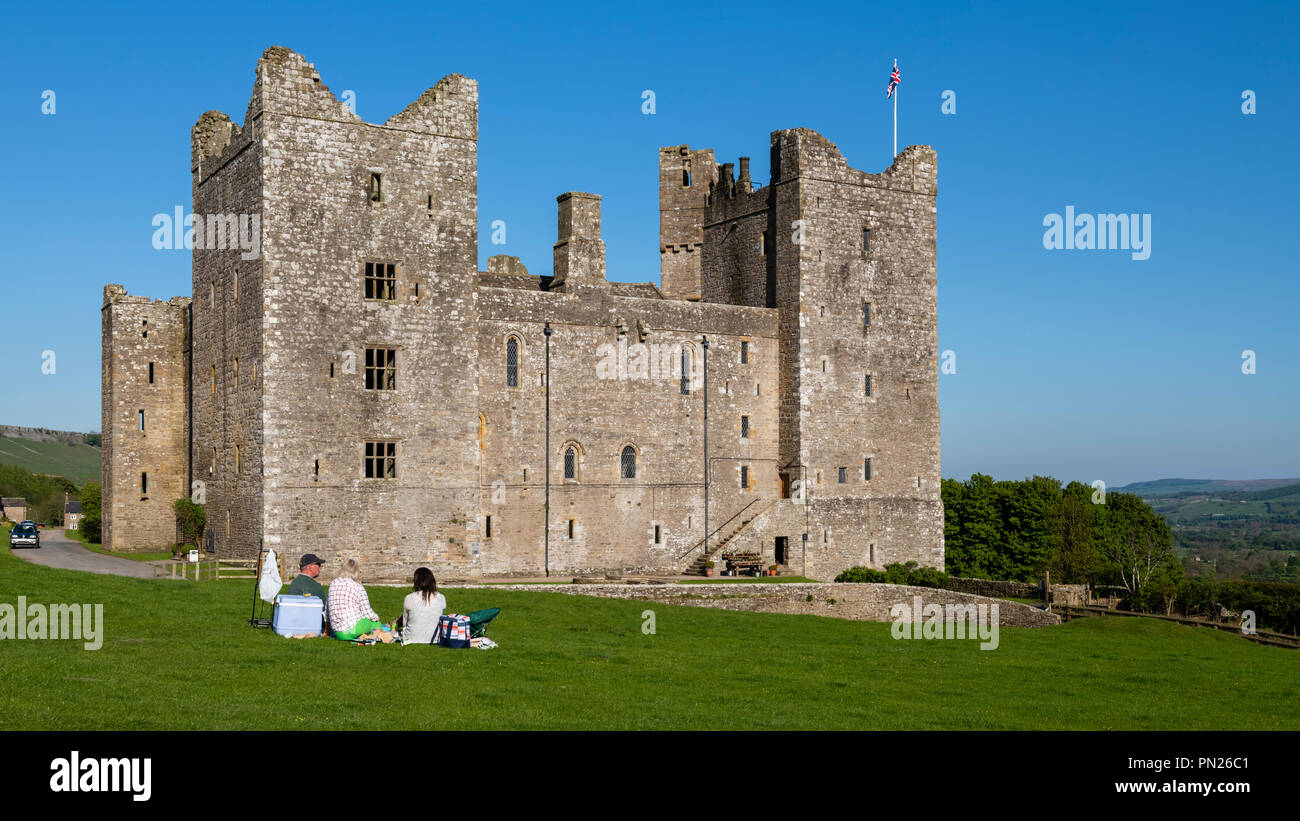 Die Leute sitzen & Picknick unter blauem Himmel durch historische mittelalterliche Burg in der wunderschönen Landschaft - Bolton Castle, Wensleydale, North Yorkshire, England, Grossbritannien Stockfoto