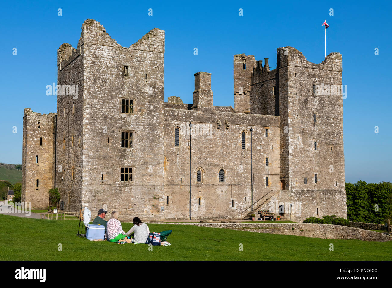 Die Leute sitzen & Picknick unter blauem Himmel durch historische mittelalterliche Burg in der wunderschönen Landschaft - Bolton Castle, Wensleydale, North Yorkshire, England, Grossbritannien Stockfoto