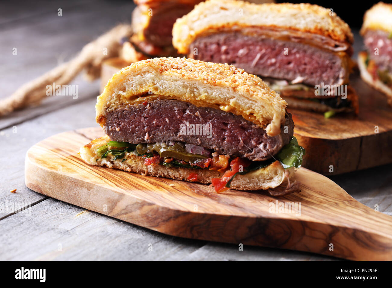 In der Hälfte der Angus Burger im kornbrötchen mit Tomaten, Salat und Relish Cheddar Stockfoto