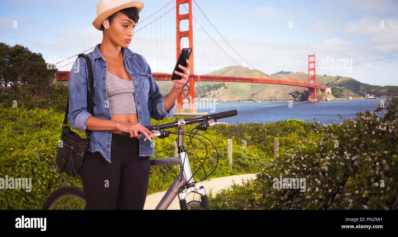 Schwarze Frau auf dem Fahrrad vor San Francisco Golden Gate Bridge mit Handy Stockfoto