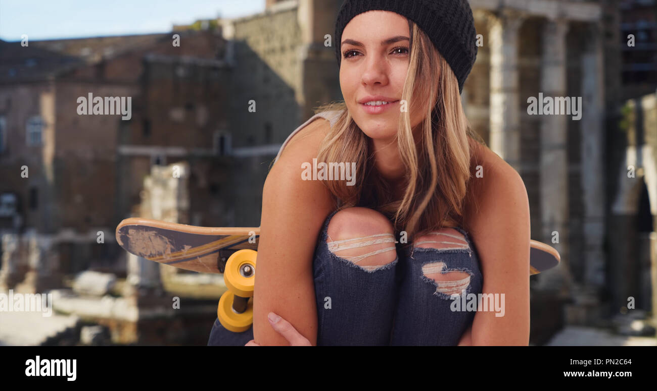 Happy kaukasische Mädchen in zerrissenen Jeans Entspannung im Freien mit ihr Skateboard Stockfoto