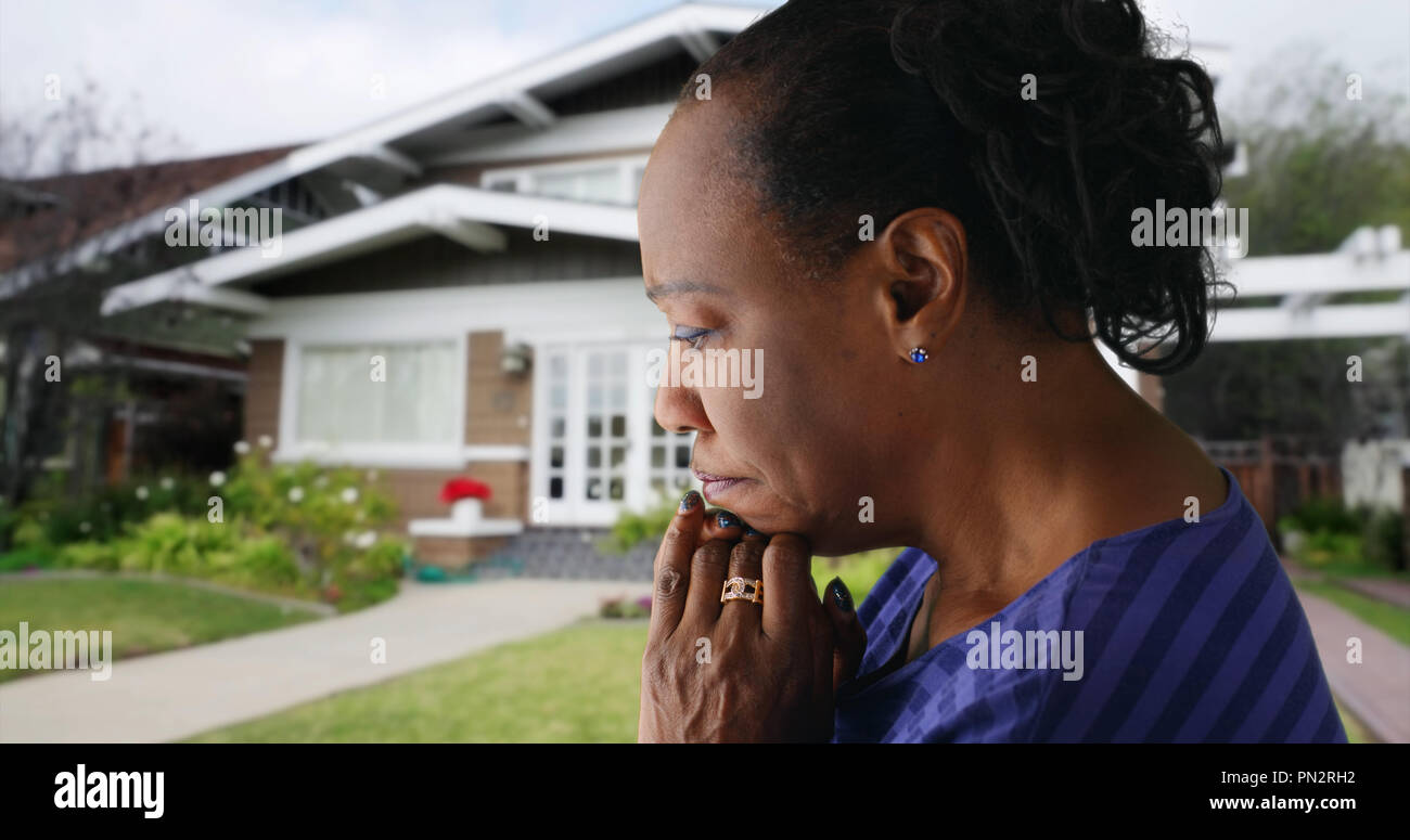 Eine ältere schwarze Frau betet außerhalb ihrer Heimat Stockfoto