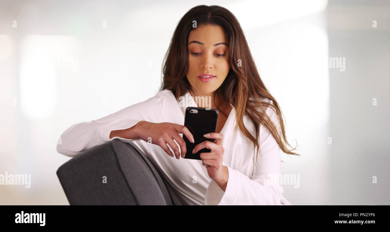 Portrait von frischem konfrontiert junge Frau im weißen Gewand Faulenzen auf der Couch und texting Stockfoto
