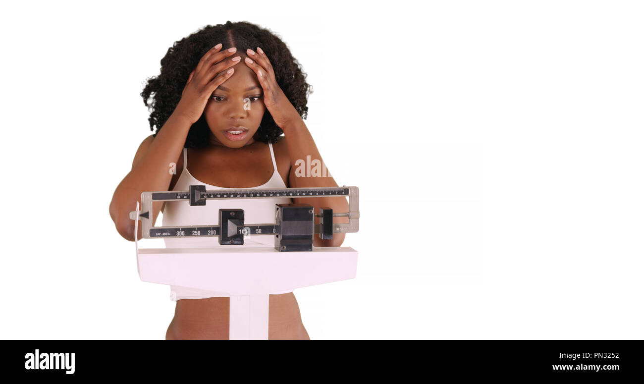 Unglückliche junge schwarze Frau wiegt sich auf der Skala in Studio mit Copyspace Stockfoto