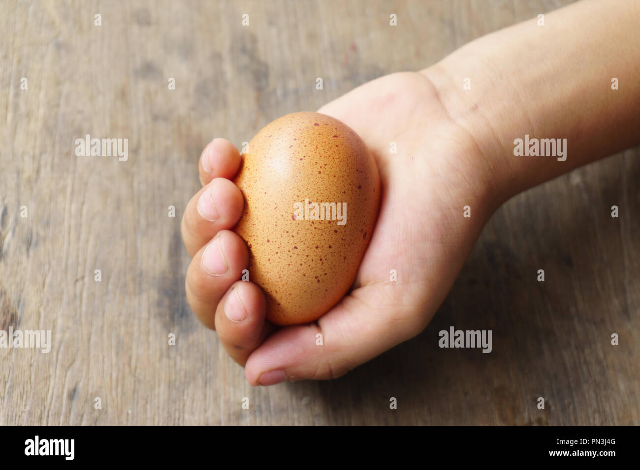 Eier in Kinderhand auf alten Holzboden. Stockfoto