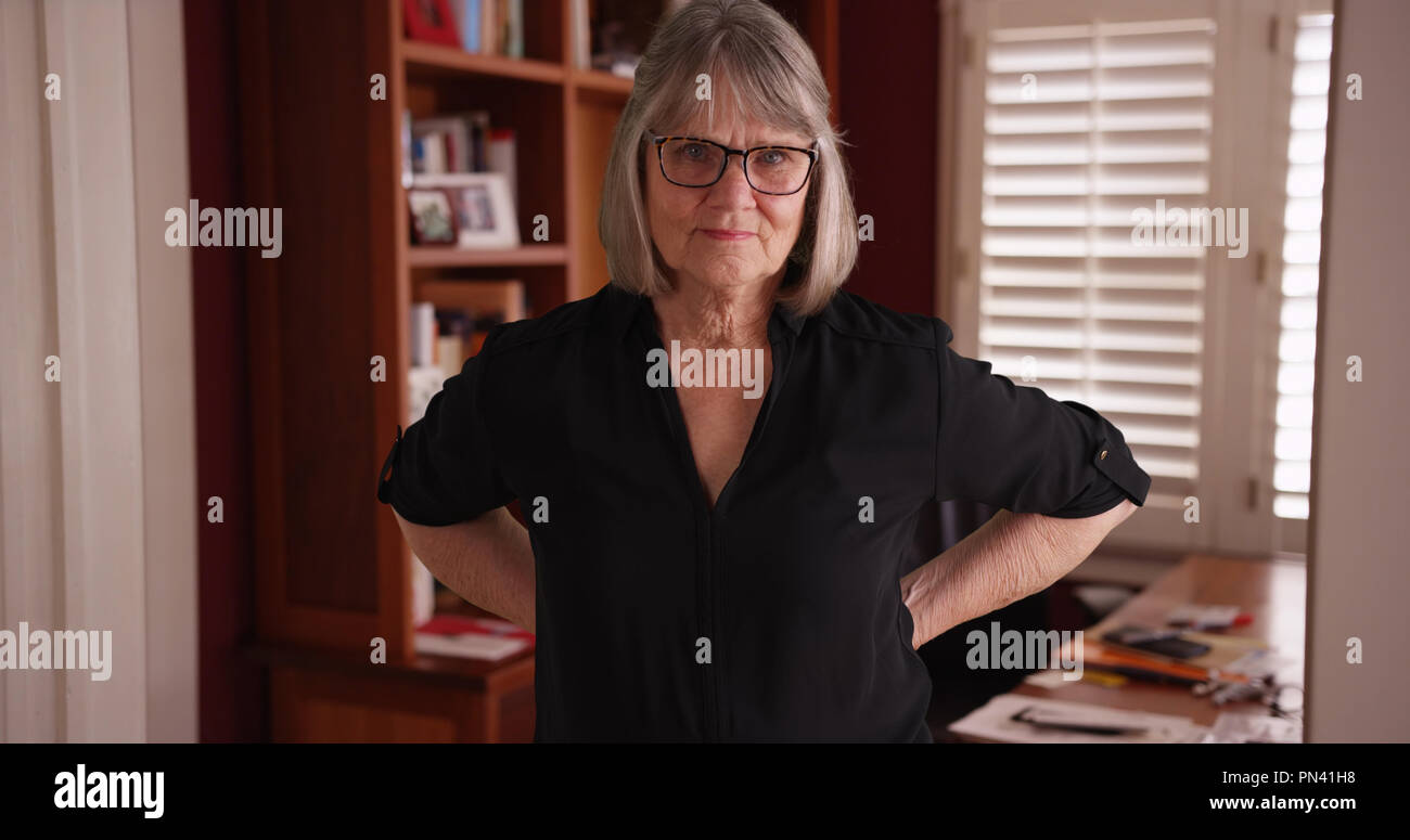 Alte weiße ältere Frau mit ernsten Einstellung in Ihrem home office Posing Stockfoto