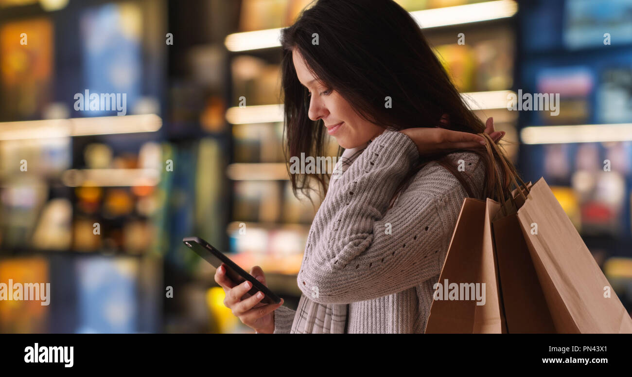Seitenansicht des tausendjährigen Frau Sms mit Handy und lächelnd Stockfoto