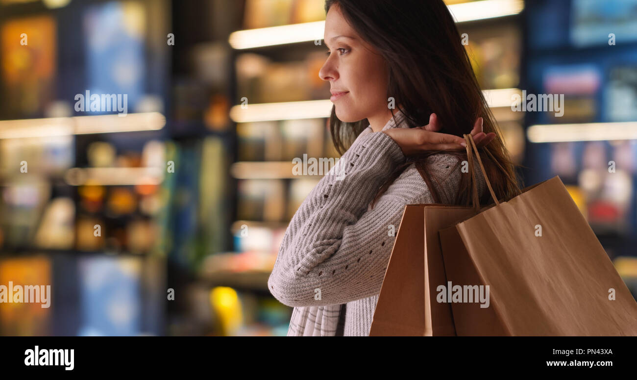Seitenansicht des tausendjährigen Frau in Store Shop warten und lächelnd Stockfoto