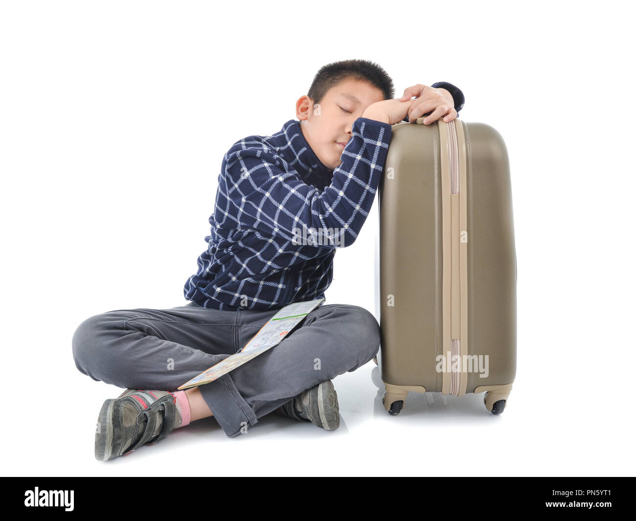 Asian Boy schlafen mit Karte und Gepäck auf weißem Hintergrund. Stockfoto