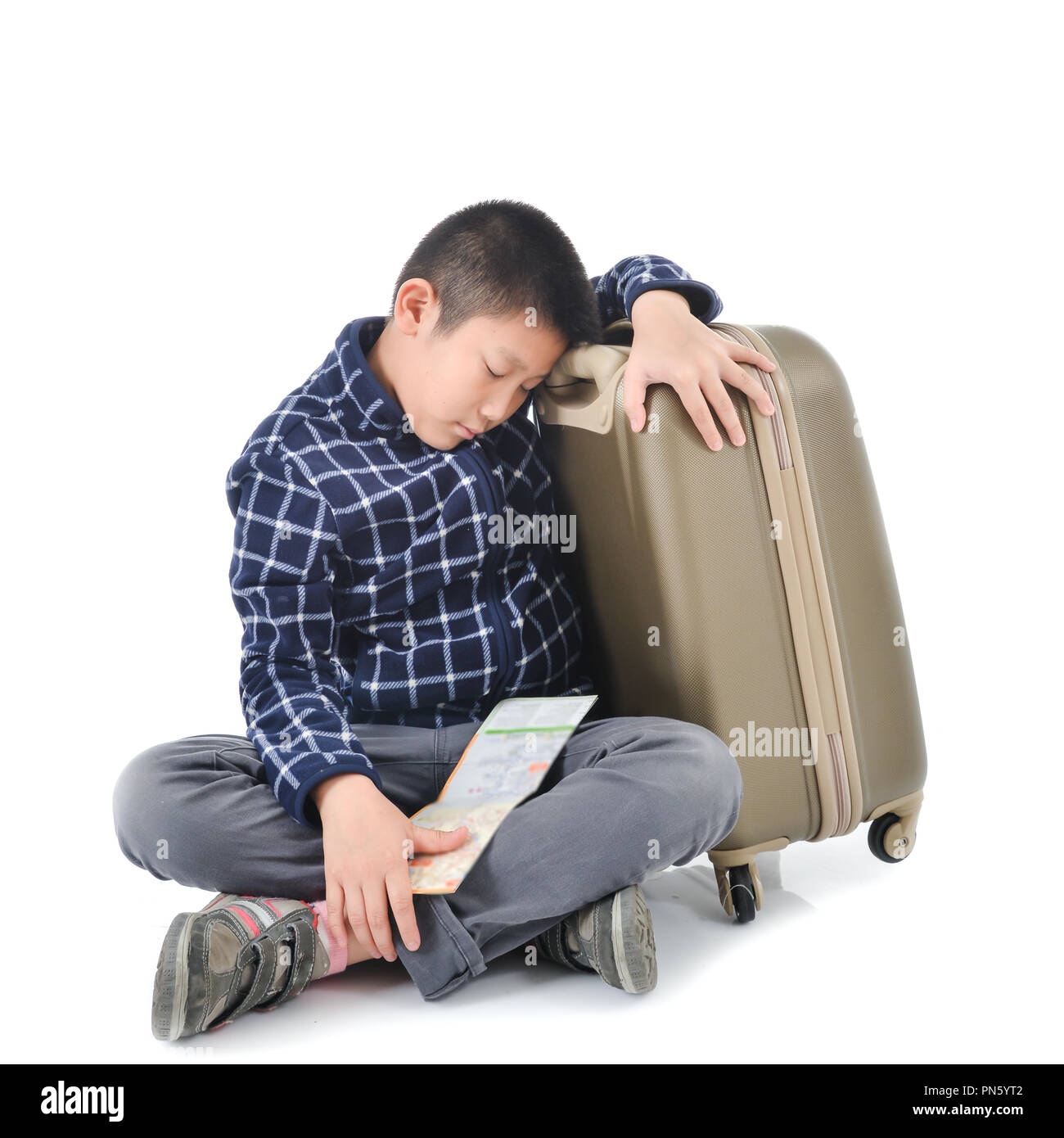 Asian Boy schlafen mit Karte und Gepäck auf weißem Hintergrund. Stockfoto