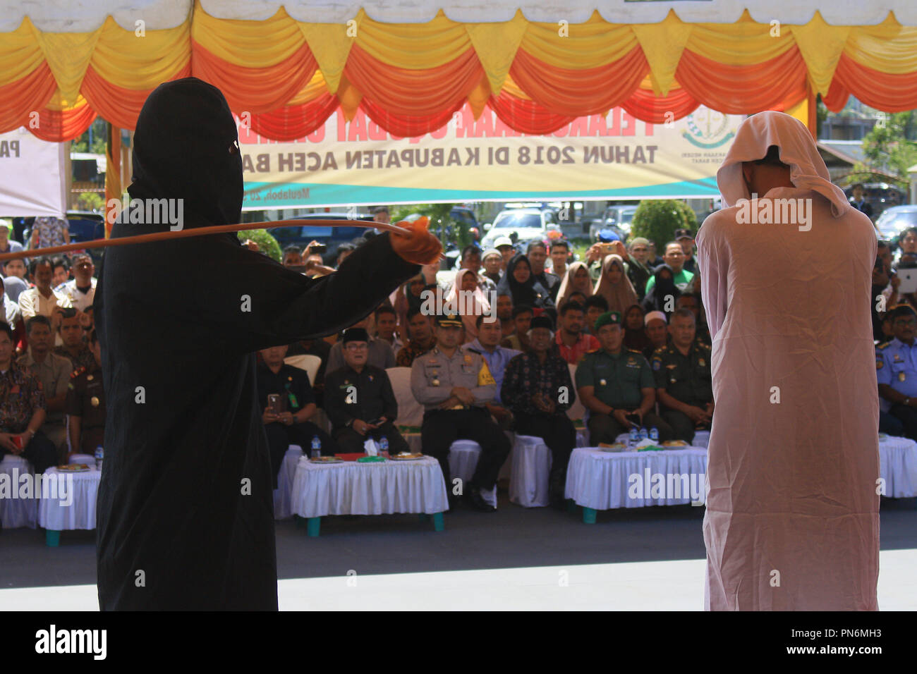 Meulaboh, Aceh, Indonesien. 20 Sep, 2018. Ein Mann gesehen auf der öffentlichen Bühne gepeitscht wird. 19 Personen (18 Männer und 1 Frau), die von der Meulaboh Scharia-gericht von im öffentlichen gepeitscht wird für Kinder sexuell mißbrauchen und Glücksspiel verurteilt wurden. Die Anwendung von Züchtigung (TREIBEND) in Aceh ist im Lichte der Öffentlichkeit erfolgt, in der Regel vor der Moschee durchgeführt die Folgen der eine abschreckende Wirkung auf die Täter, die islamische Scharia verstoßen anzuzeigen. Trotz Kritik von Seiten der internationalen Gemeinschaft, bis jetzt Aceh immer noch die islamische Scharia gilt. (Bild: © Mimi Saputra/SOPA Imag Stockfoto