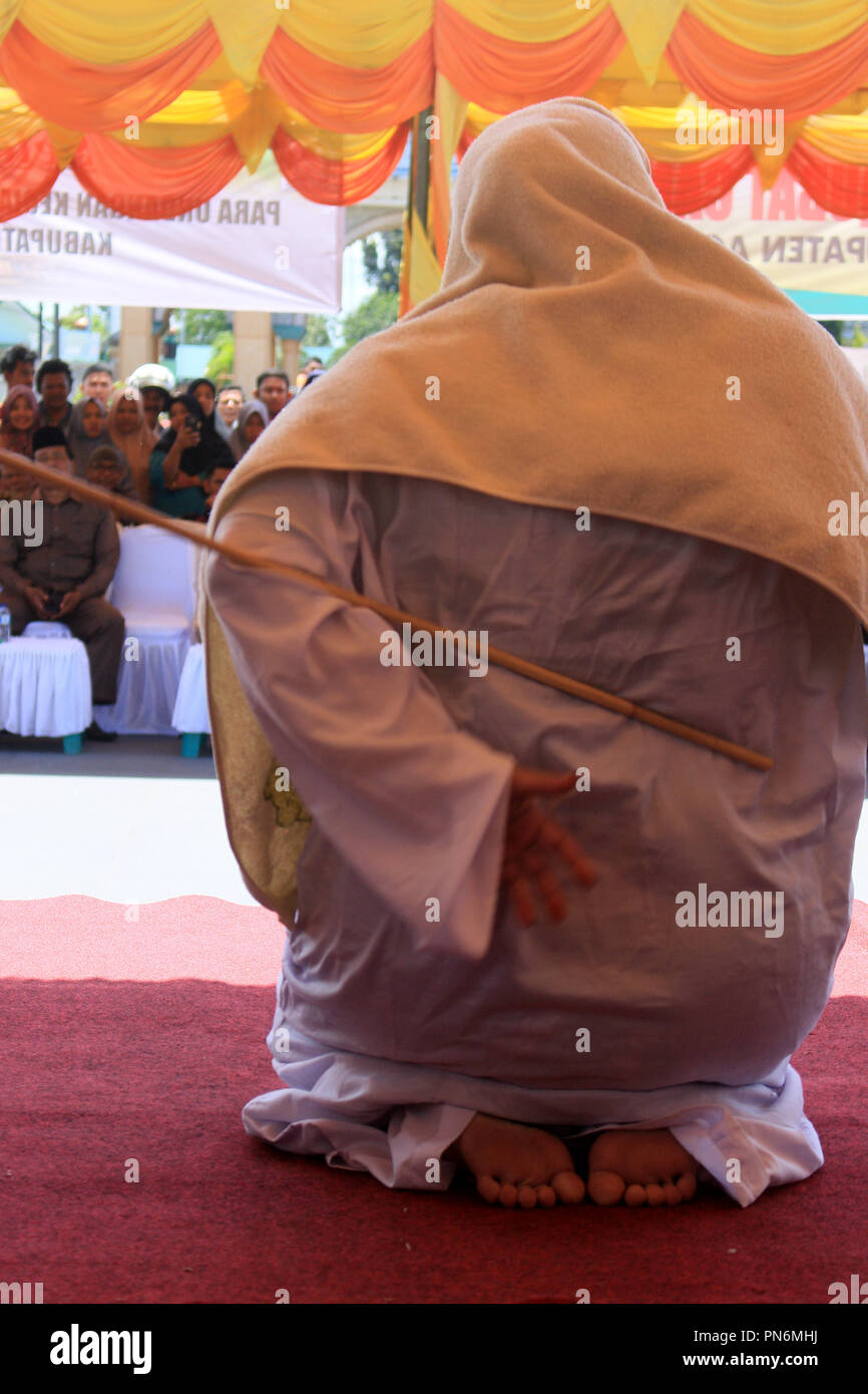 Meulaboh, Aceh, Indonesien. 20 Sep, 2018. Eine Frau gesehen auf der öffentlichen Bühne gepeitscht wird. 19 Personen (18 Männer und 1 Frau), die von der Meulaboh Scharia-gericht von im öffentlichen gepeitscht wird für Kinder sexuell mißbrauchen und Glücksspiel verurteilt wurden. Die Anwendung von Züchtigung (TREIBEND) in Aceh ist im Lichte der Öffentlichkeit erfolgt, die in der Regel durchgeführt vor der Moschee die Folgen der eine abschreckende Wirkung auf die Täter, die islamische Scharia verstoßen anzuzeigen. Trotz Kritik von Seiten der internationalen Gemeinschaft, bis jetzt Aceh immer noch die islamische Scharia gilt. (Bild: © Mimi Saputra/SOPA Im Stockfoto