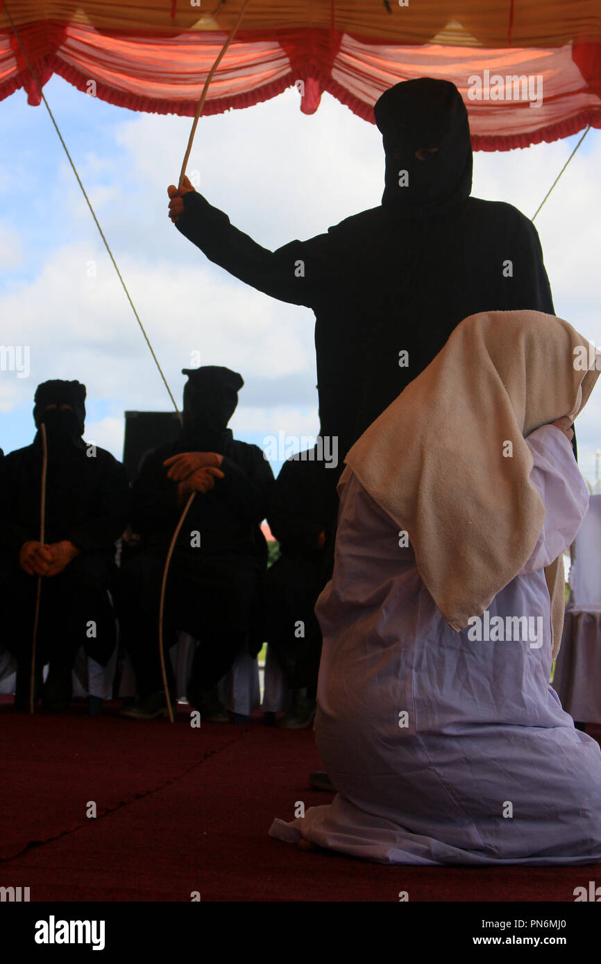 Meulaboh, Aceh, Indonesien. 20 Sep, 2018. Eine Frau gesehen auf der öffentlichen Bühne gepeitscht wird. 19 Personen (18 Männer und 1 Frau), die von der Meulaboh Scharia-gericht von im öffentlichen gepeitscht wird für Kinder sexuell mißbrauchen und Glücksspiel verurteilt wurden. Die Anwendung von Züchtigung (TREIBEND) in Aceh ist im Lichte der Öffentlichkeit erfolgt, die in der Regel durchgeführt vor der Moschee die Folgen der eine abschreckende Wirkung auf die Täter, die islamische Scharia verstoßen anzuzeigen. Trotz Kritik von Seiten der internationalen Gemeinschaft, bis jetzt Aceh immer noch die islamische Scharia gilt. (Bild: © Mimi Saputra/SOPA Im Stockfoto