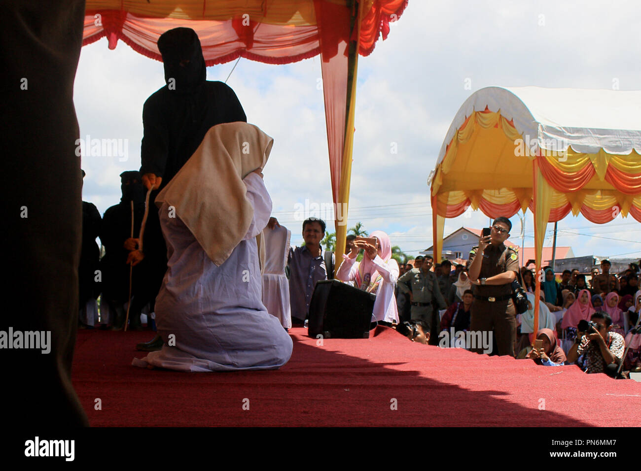Meulaboh, Aceh, Indonesien. 20 Sep, 2018. Eine Frau gesehen auf der öffentlichen Bühne gepeitscht wird. 19 Personen (18 Männer und 1 Frau), die von der Meulaboh Scharia-gericht von im öffentlichen gepeitscht wird für Kinder sexuell mißbrauchen und Glücksspiel verurteilt wurden. Die Anwendung von Züchtigung (TREIBEND) in Aceh ist im Lichte der Öffentlichkeit erfolgt, die in der Regel durchgeführt vor der Moschee die Folgen der eine abschreckende Wirkung auf die Täter, die islamische Scharia verstoßen anzuzeigen. Trotz Kritik von Seiten der internationalen Gemeinschaft, bis jetzt Aceh immer noch die islamische Scharia gilt. (Bild: © Mimi Saputra/SOPA Im Stockfoto