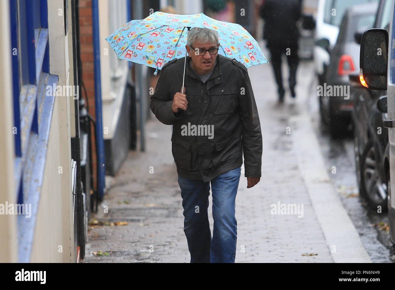 Menschen zu Fuß auf der Straße im Regen mit Sonnenschirmen. Großbritannien Stockfoto
