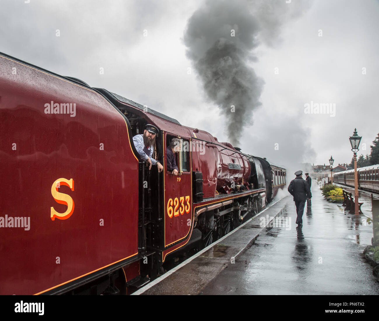 Kidderminster, Großbritannien. 20. September, 2018. UK Wetter: Das Personal an der Severn Valley Railway Soldat auf, obwohl der Regen fort. Anhaltender Regen nicht die Geister der Angestellten oder Reisenden dämpfen als 6233 Dampflok, Herzogin von Sutherland, fährt von Kidderminster station Überschrift nach Bridgnorth. Anfahren, er wirft aus Federn von Dampf in die feuchte Luft auf den frühen Morgen laufen für den Beginn des SVR Herbst Dampf Gala. Quelle: Lee Hudson/Alamy leben Nachrichten Stockfoto