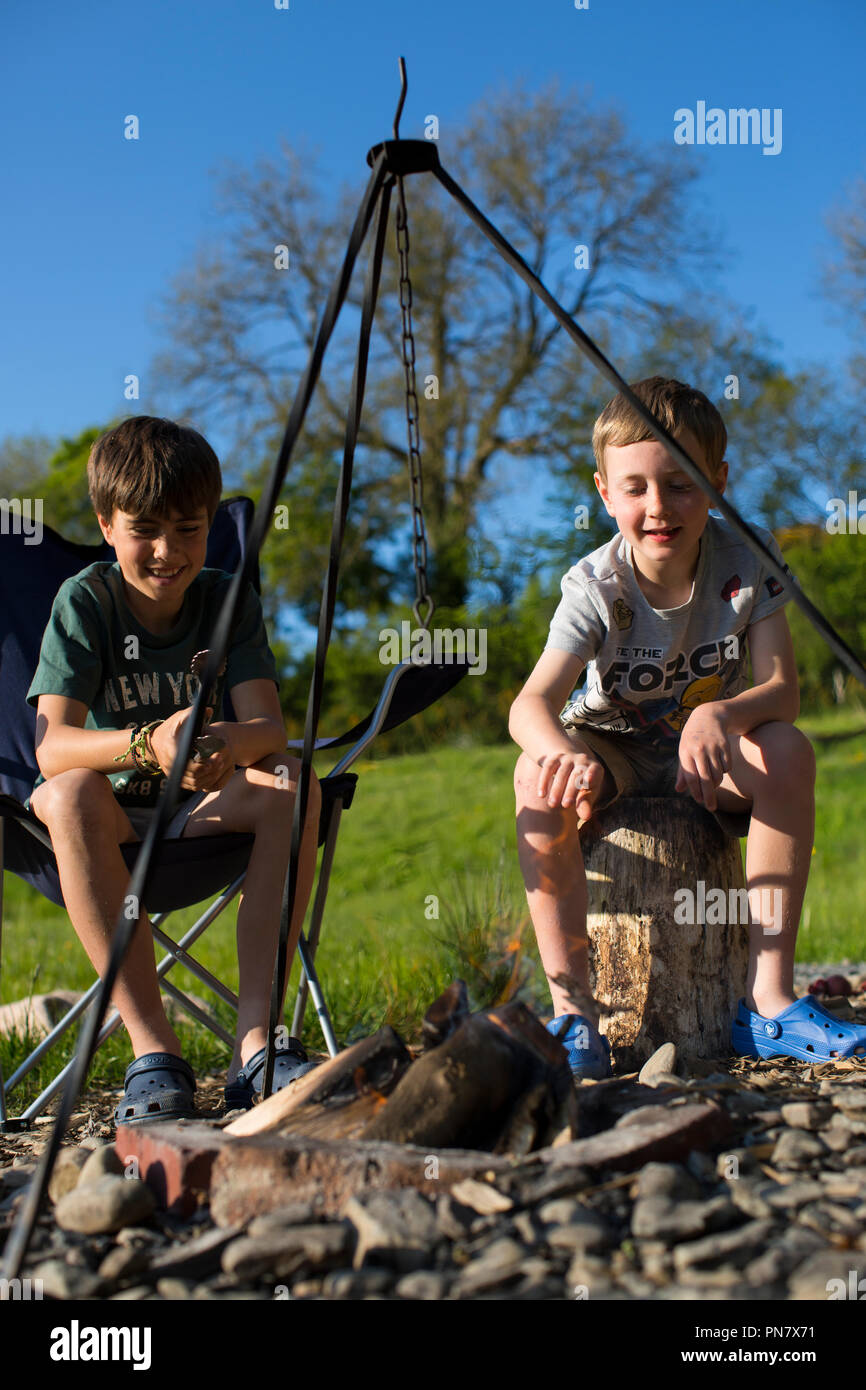 Zwei Jungen kochen und Sprechen rund um ein Lagerfeuer. Stockfoto