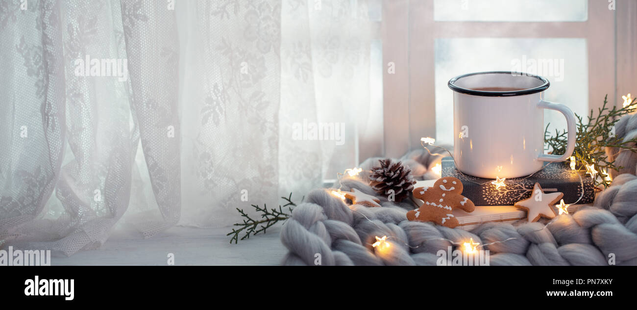 Tasse Kaffee mit Weihnachtsbeleuchtung in der Nähe der Fenster Stockfoto