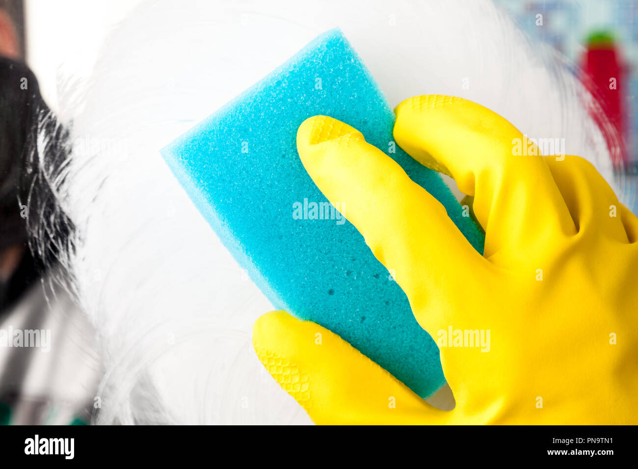 Person, Aufgaben im Bad zu Hause Reinigung Spiegel mit Reinigungsmittel und Schwamm Stockfoto