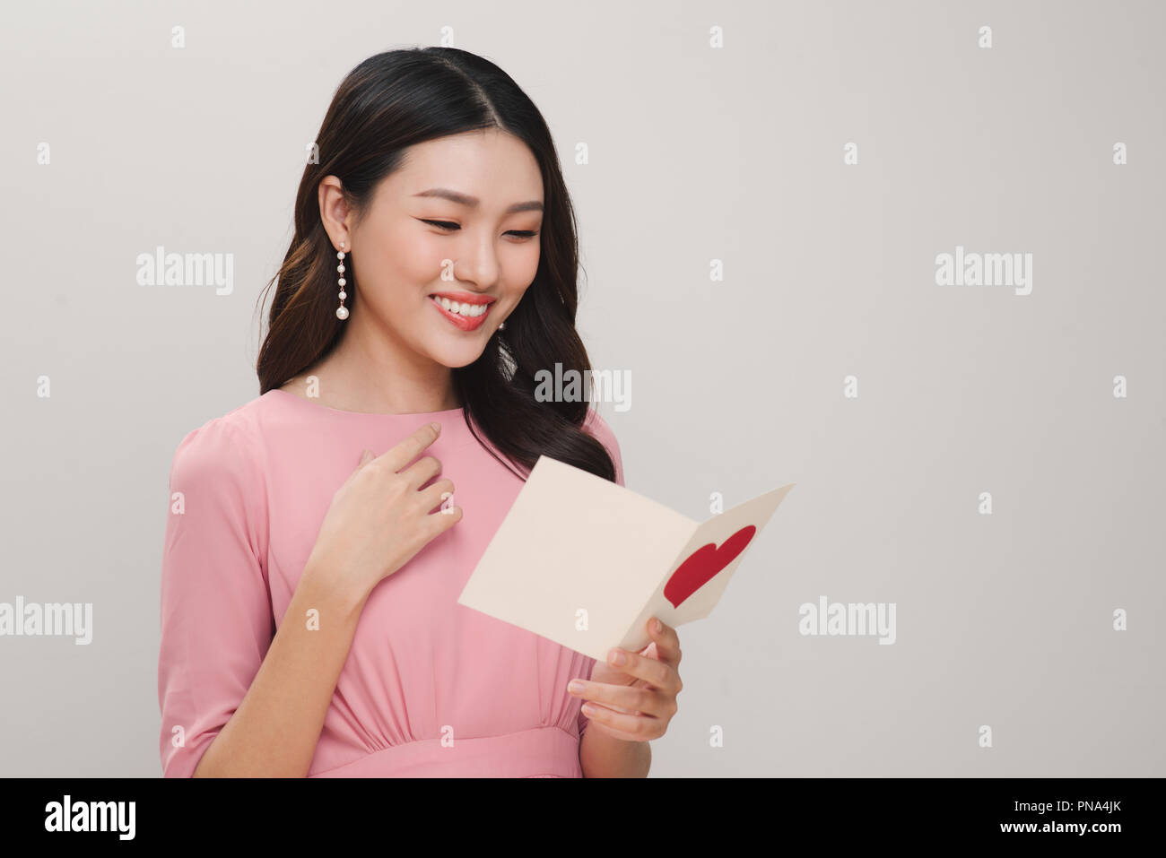 Junge schöne lächelnde Frau mit Postkarte auf weißem Hintergrund. St. Valentines Tag oder Tag der internationalen Frauen Konzept Stockfoto