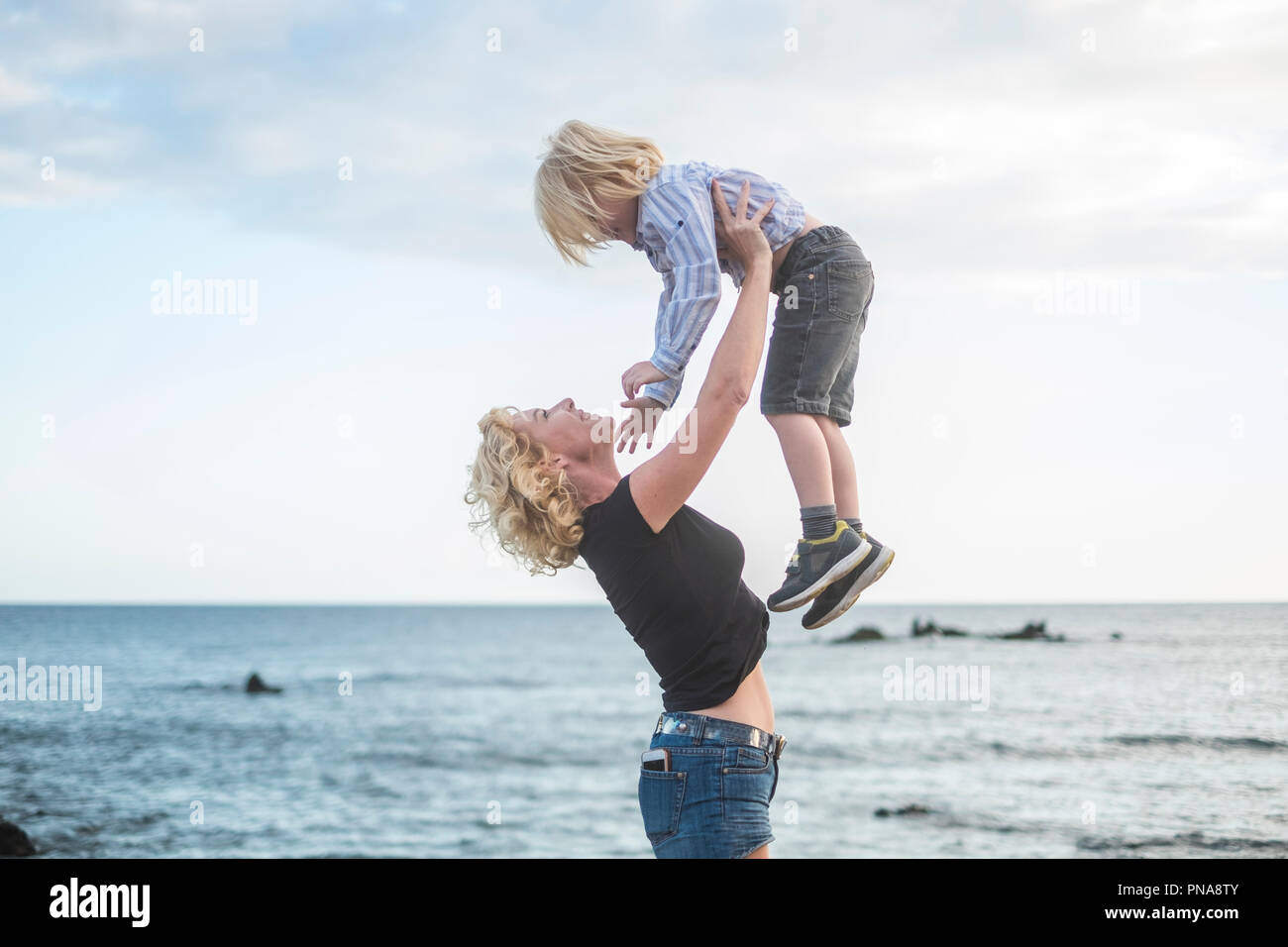 Freude und Glück Konzept mit Liebe zwischen kaukasischen Frau und junge Mutter und Sohn umarmen und spielen in Urlaub Freizeitaktivitäten Kalendertage mit Sonnen Stockfoto