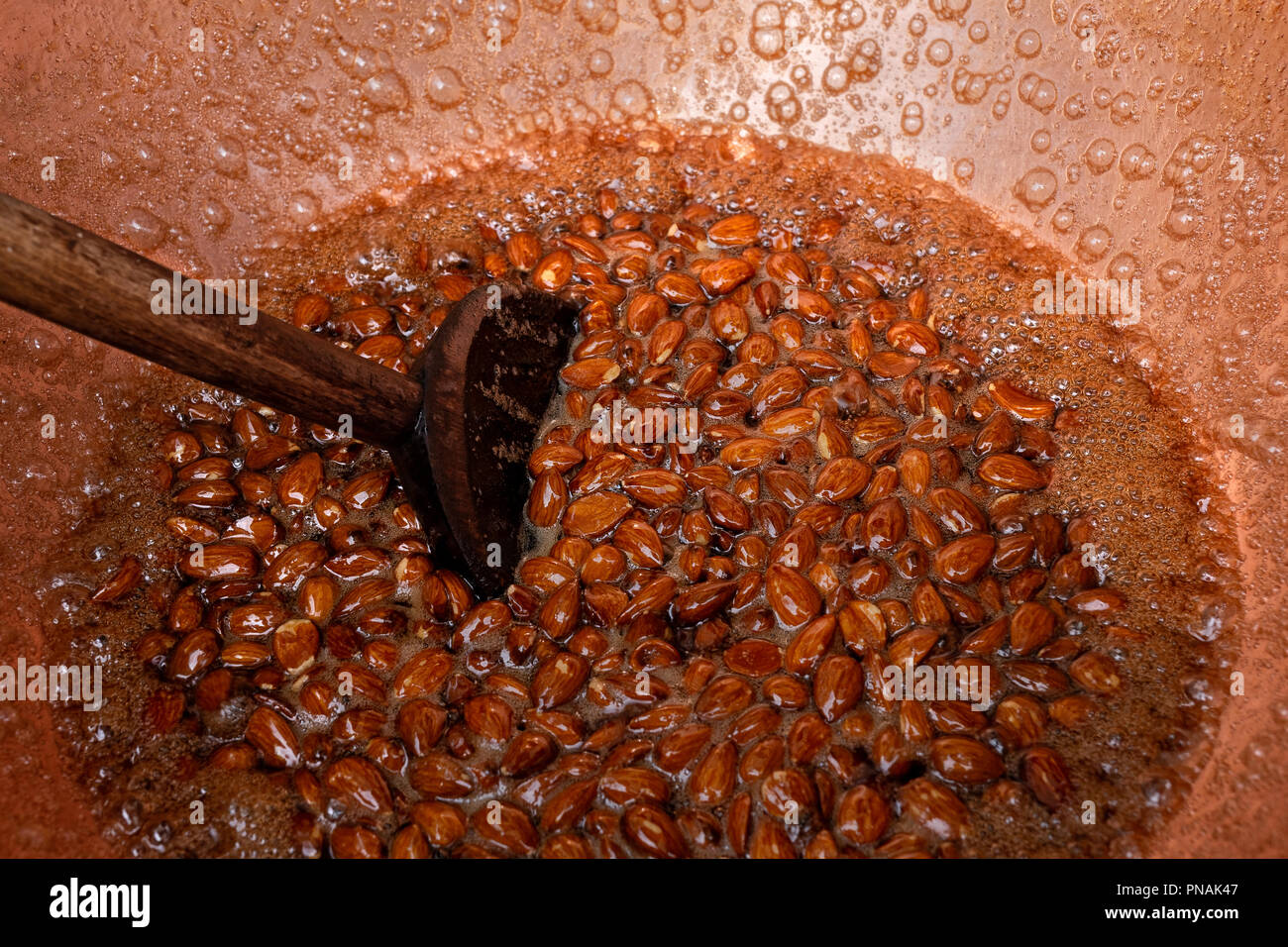 Zucker überzogen Mandeln werden von Hand geröstet. Stockfoto