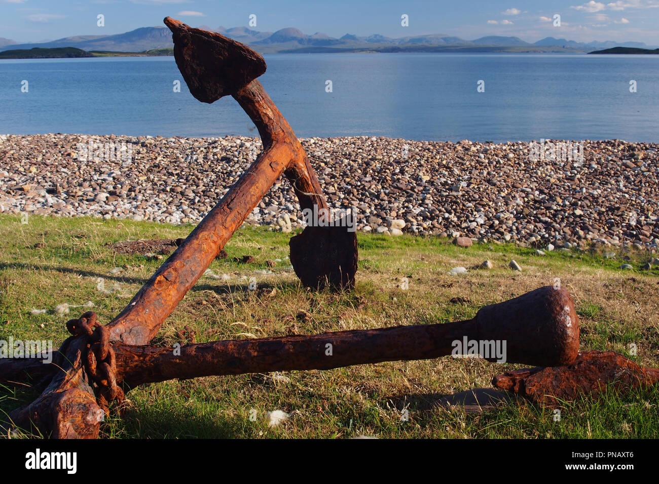 Eine alte rostige, alte Bügeleisen auf das Gras an der Spitze der Badentarbat Strand, Coigach, Schottland mit dem Meer und den Bergen im Hintergrund Anker abgebrochen Stockfoto