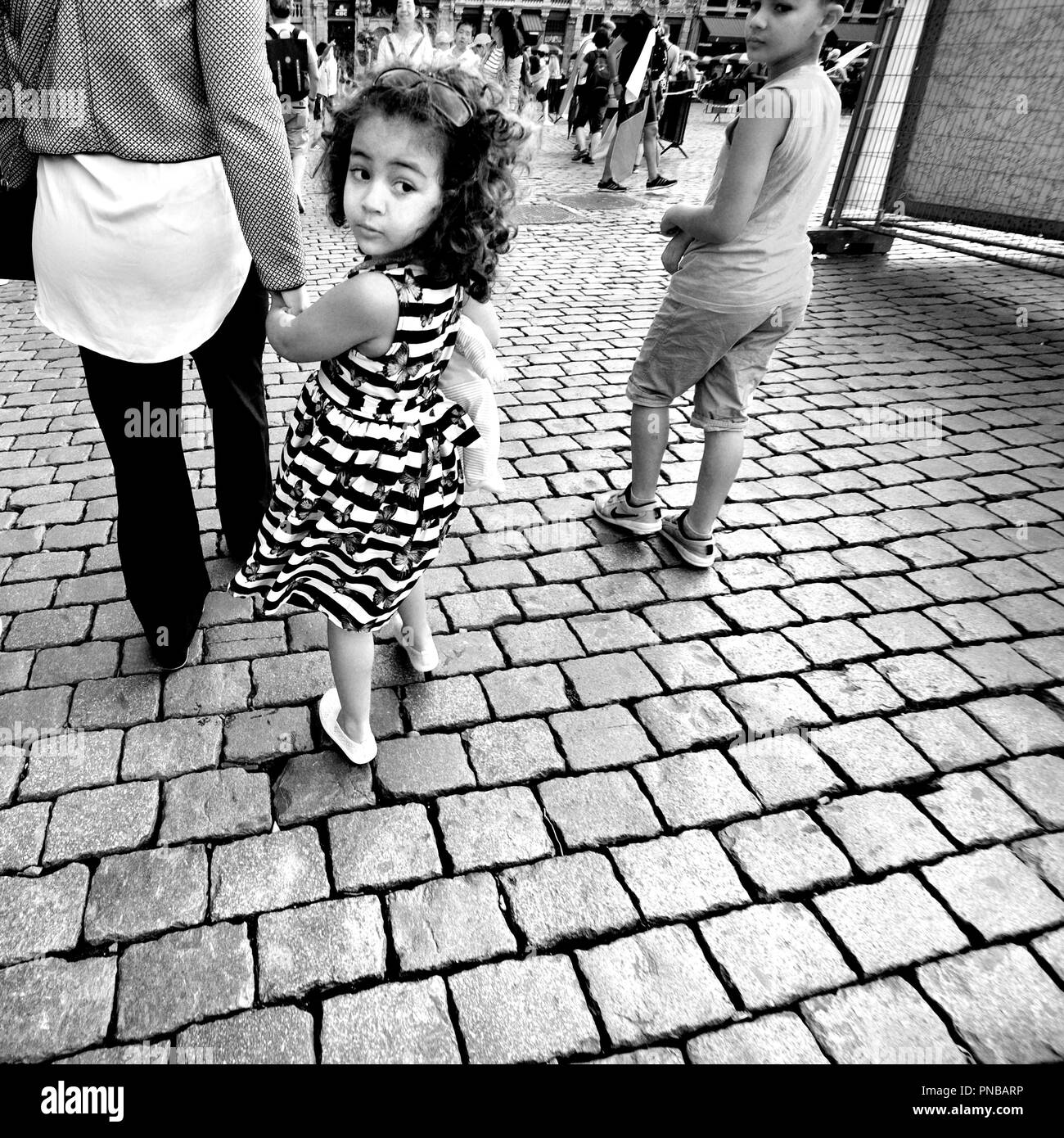 Brüssel, Belgien. Junge Mädchen die Hand ihrer Mutter Holding, Blick zurück Stockfoto