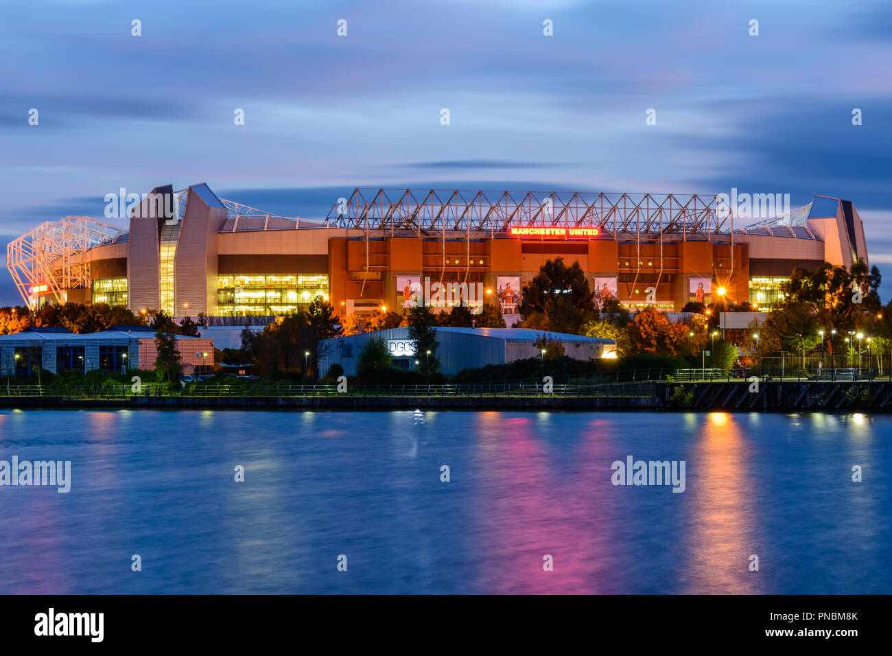 Fußballstadion Old Trafford beleuchtet Nacht gesehen von Salford Quays Stockfoto