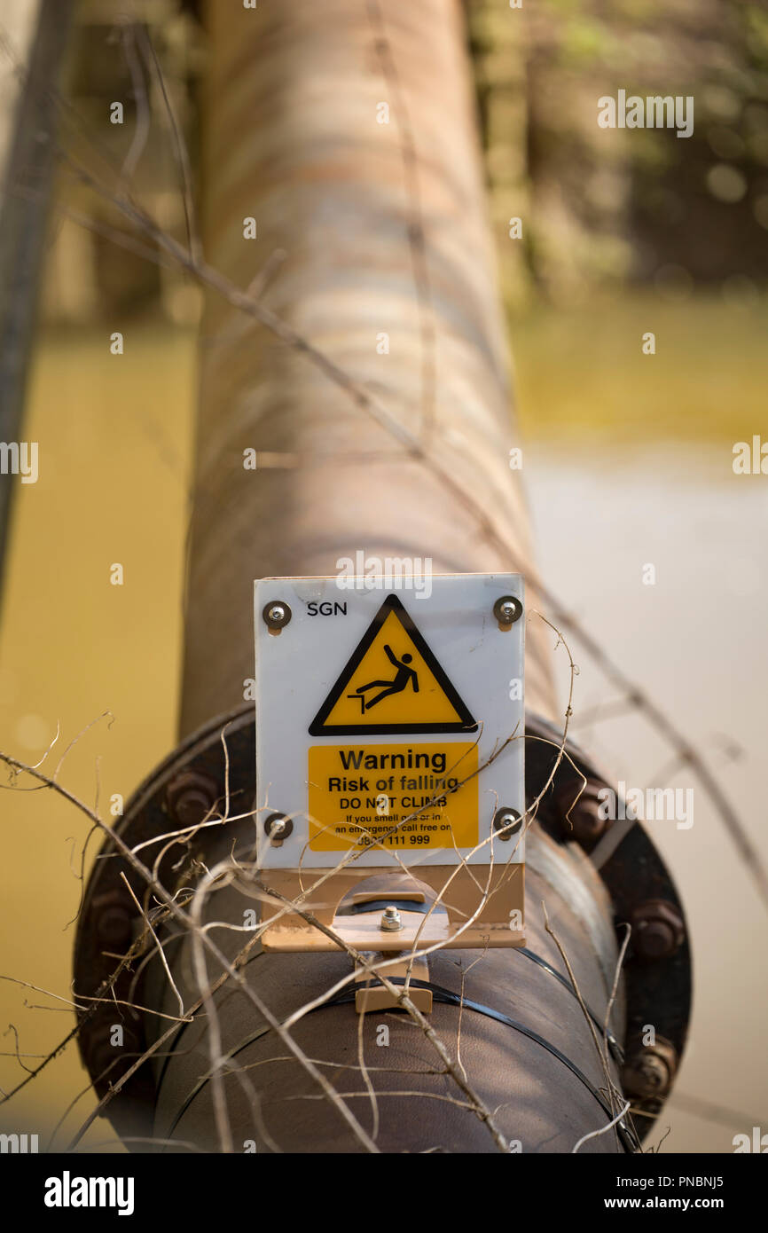Warnschild an einem Rohr über einem Fluss neben einer Brücke keine Warnung an, um es zu klettern. Dorset England UK GB Stockfoto