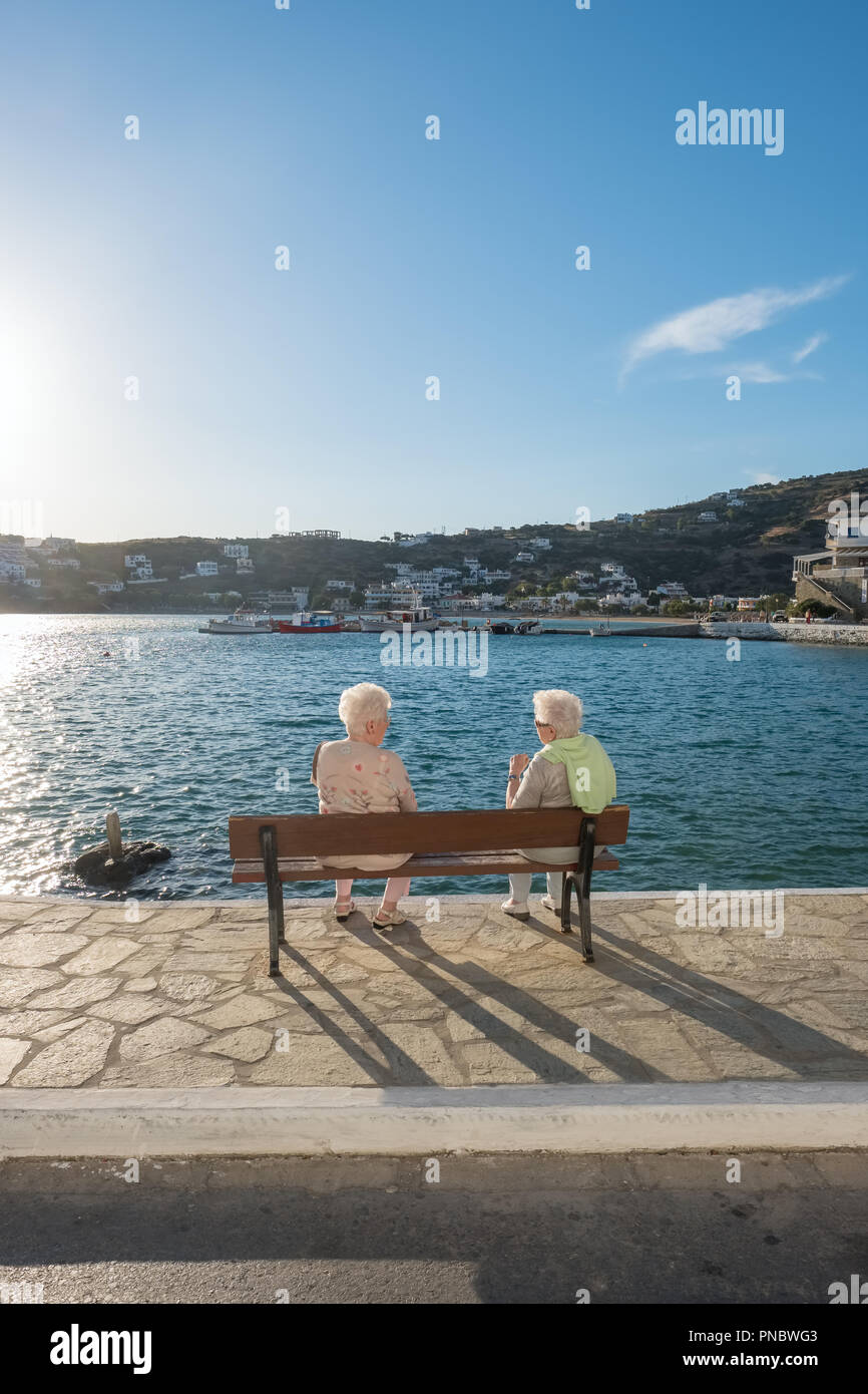 Batsi, Griechenland - 31. Mai 2018: Unbekannter älteren Damen Gespräche am Meer Bank im malerischen Dorf Batsi auf Andros, Kykladen, Griechenland Stockfoto