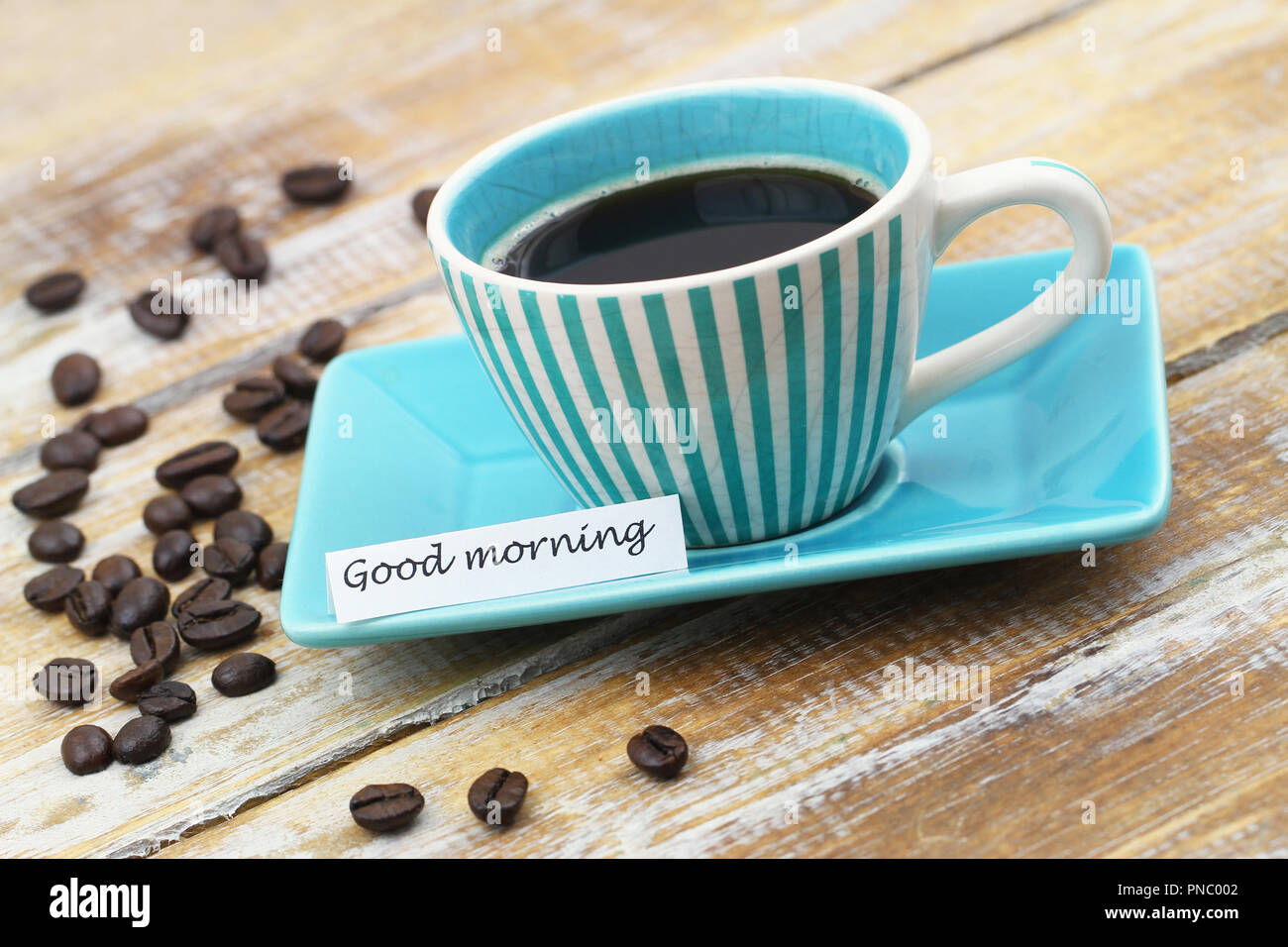 Guten Morgen Karte mit Tasse Kaffee und Kaffeebohnen auf Holzmöbeln im Landhausstil Oberfläche Stockfoto