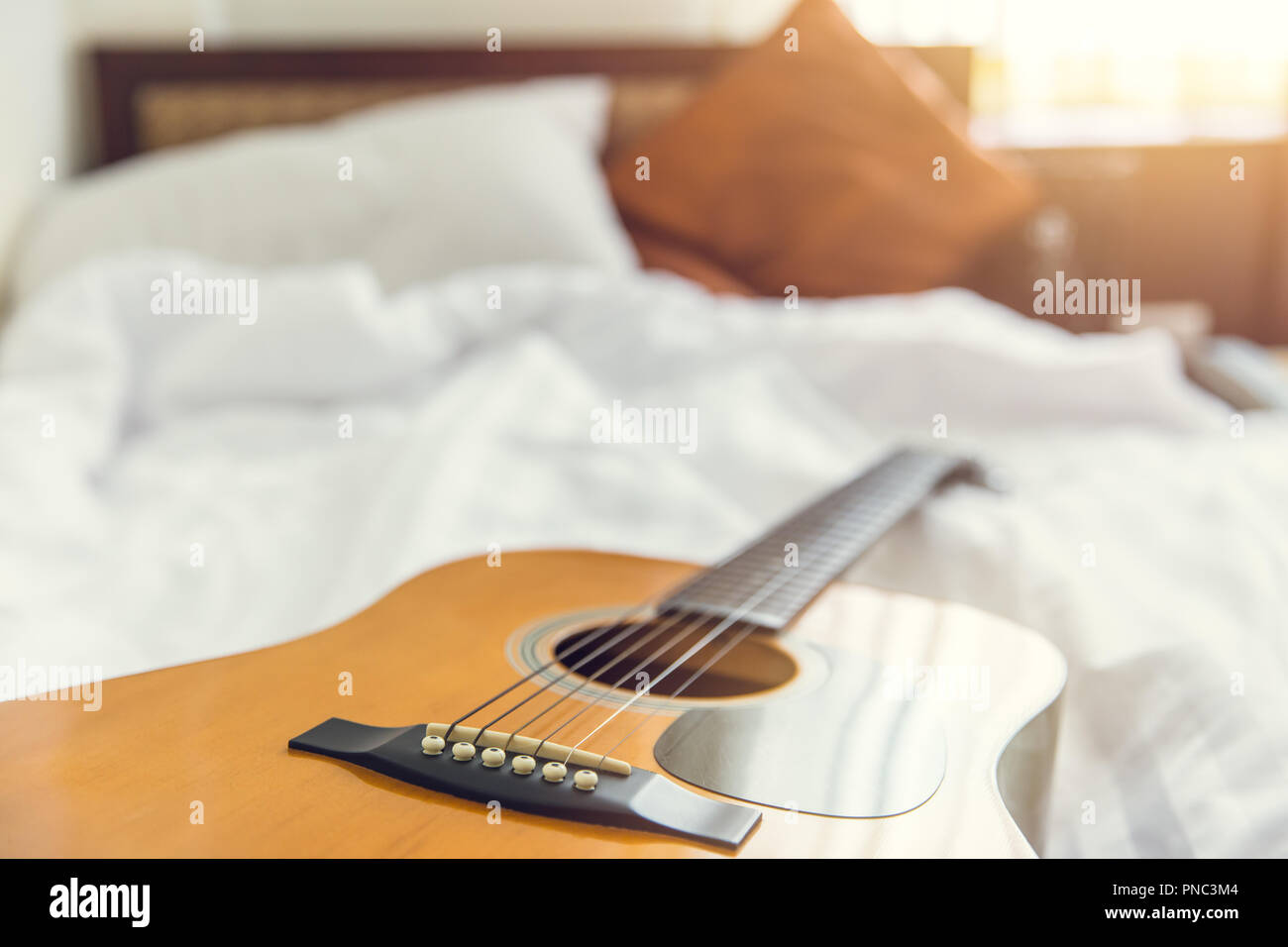 Musik im Schlafzimmer morgen Konzept. Gitarre mit weißer Bettwäsche. Stockfoto