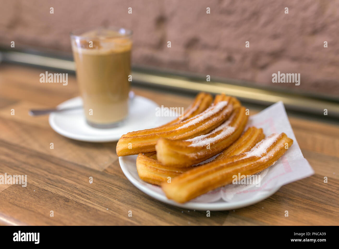 Churros und Milch Kaffee in traditionellen spanischen churreria in Barcelona, Spanien. Stockfoto