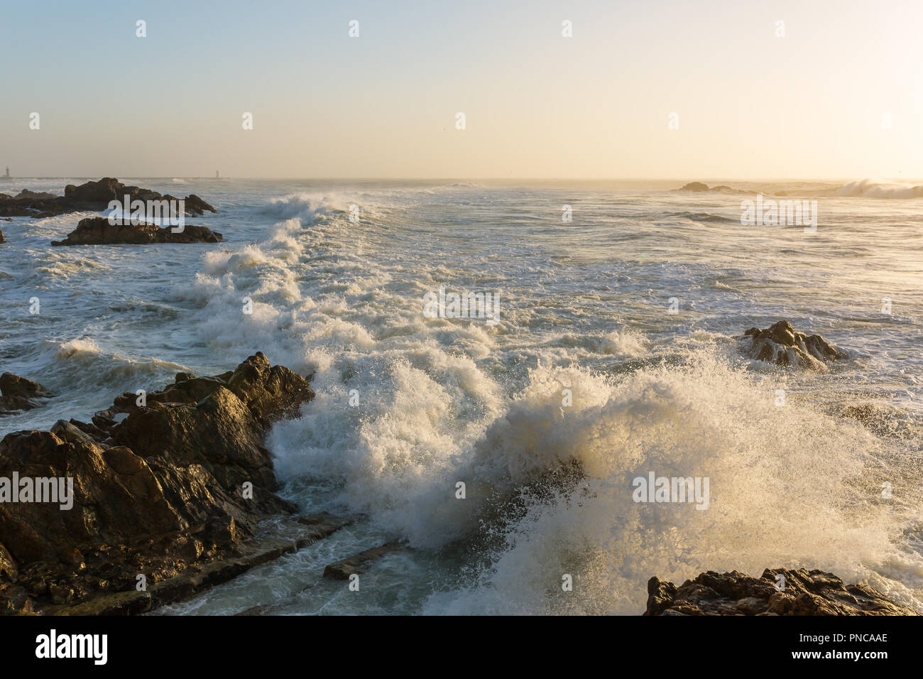 Stürmische Wellen über felsige Küste bei Sonnenuntergang Stockfoto