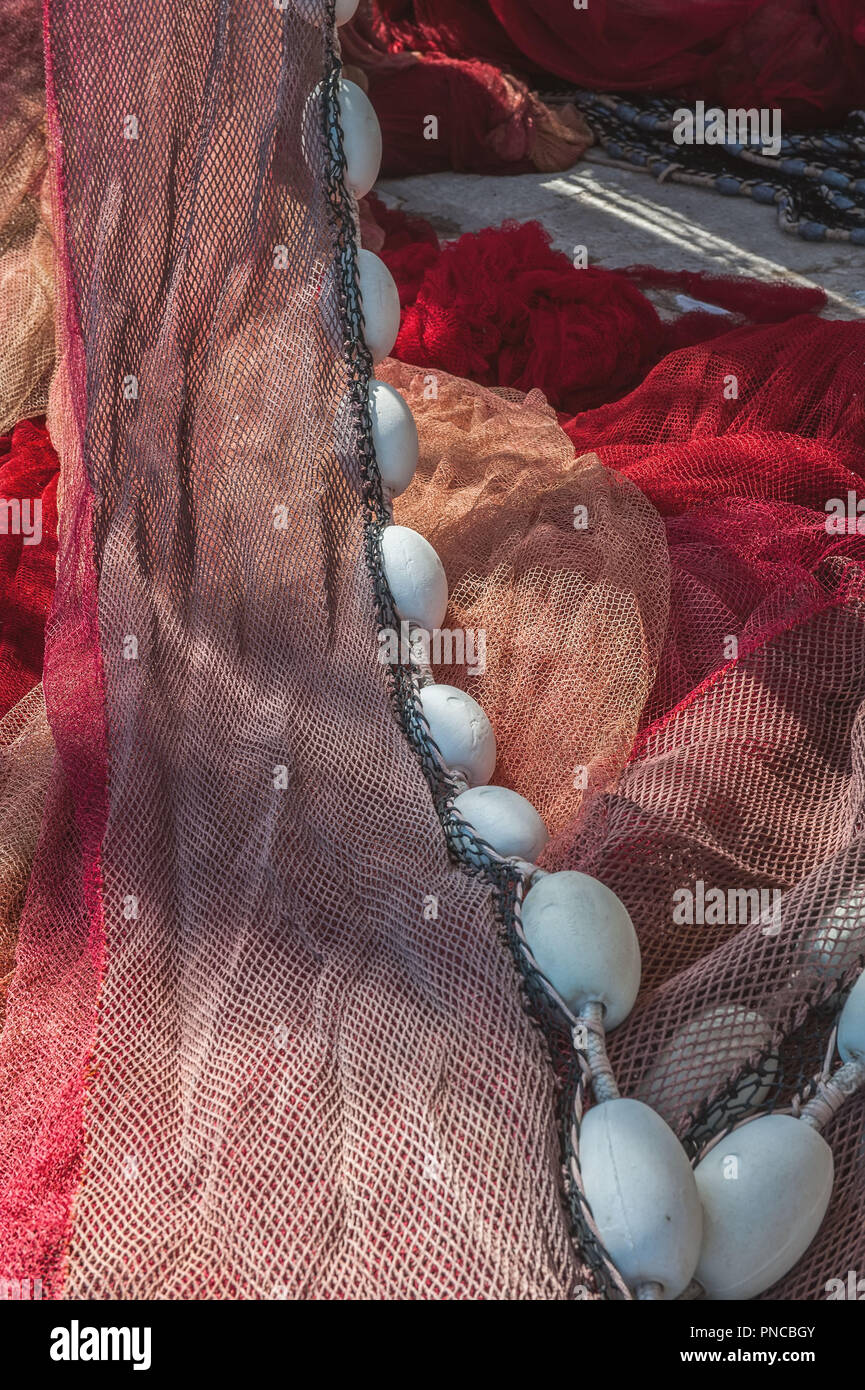 Mehrfarbige Fischernetze sind auf der Pier am Meer getrocknet. Fisch Produktion Stockfoto
