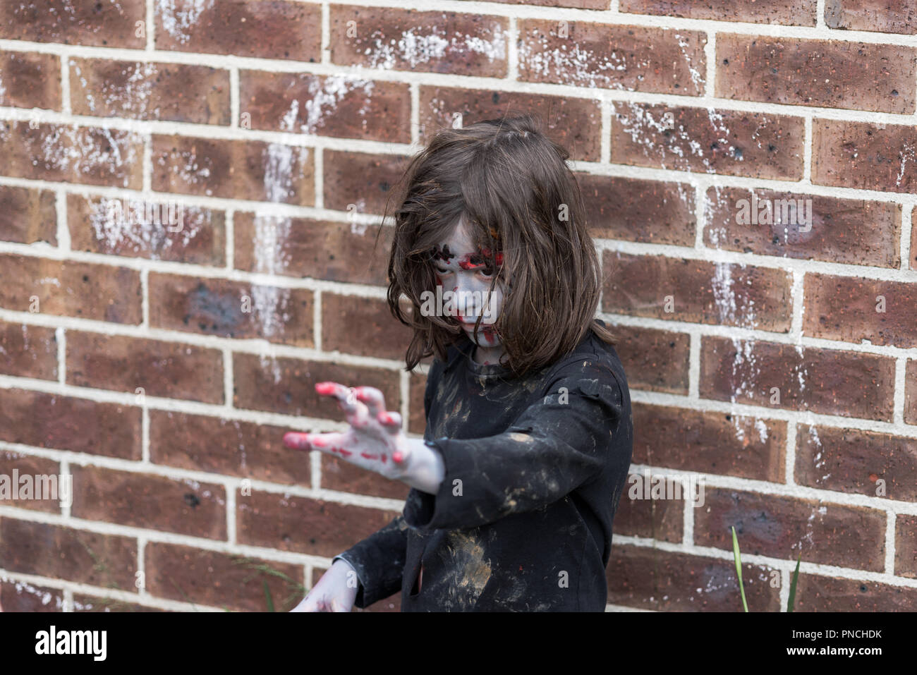 Junge Mädchen Zombie, die sich bedrohlich und erschreckend vor, die neben einer Wand Stockfoto