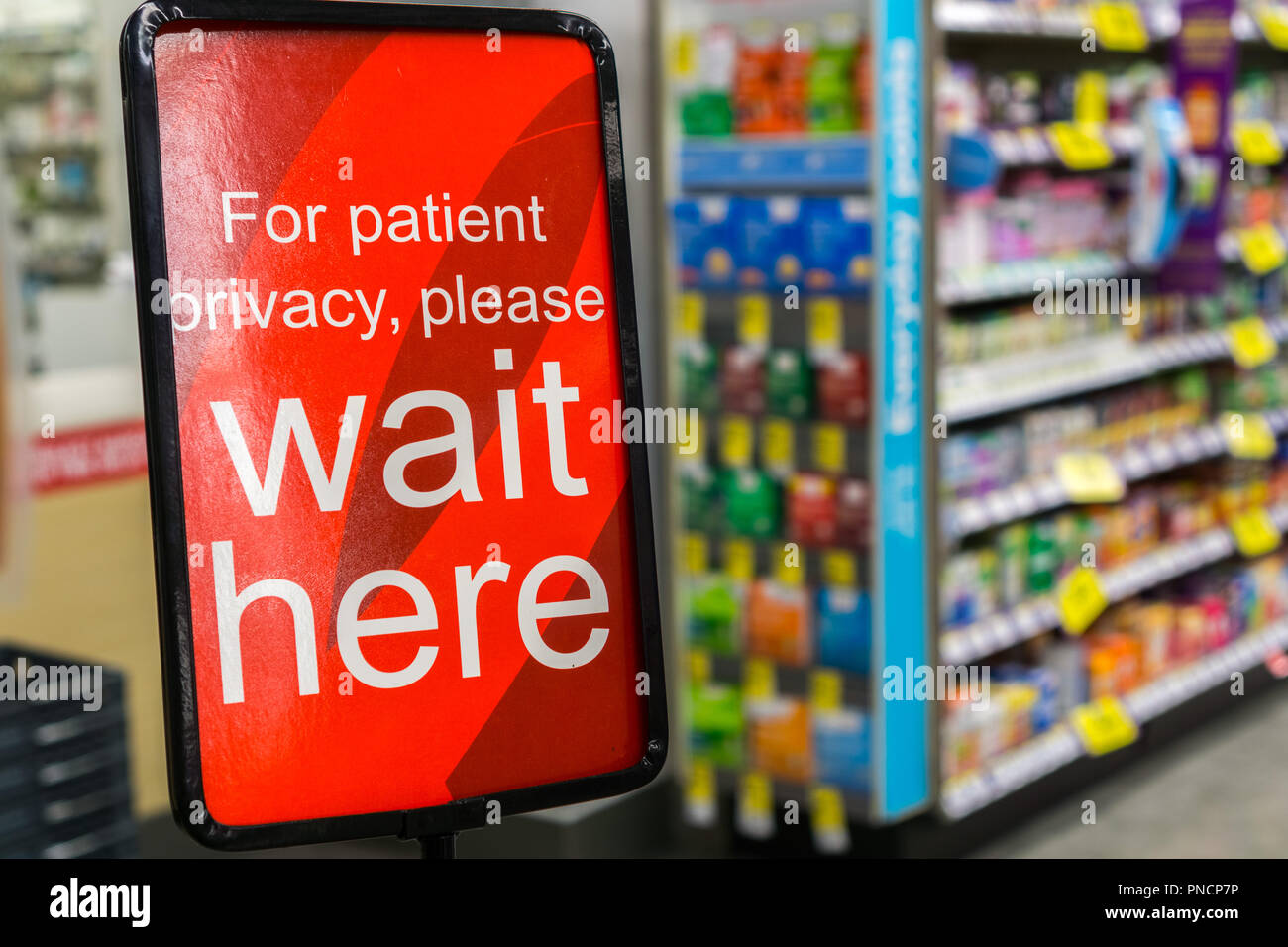 "Für die Privatsphäre der Patienten warten Sie bitte hier" Schild in einer Apotheke Stockfoto