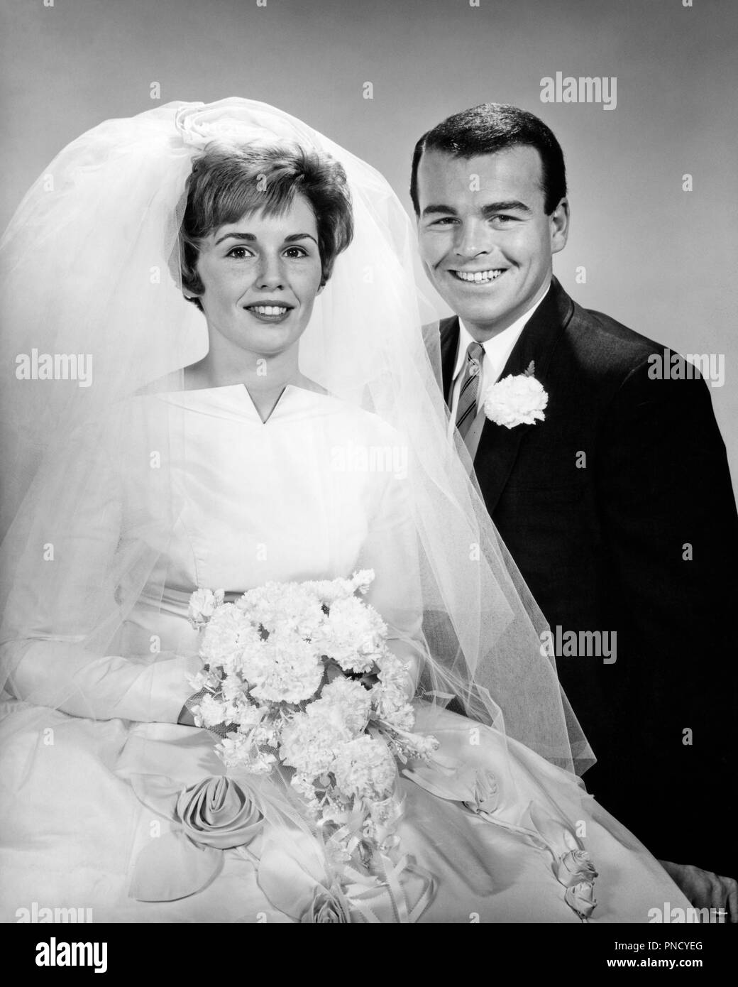 1960 Portrait von Glücklich lächelnde Braut und Bräutigam IN HOCHZEIT KLEIDER ERGEBNISSE KAMERA-b 20909 HAR 001 HARS INSPIRATION RISIKO SCHLEIER SPIRITUALITÄT VERTRAUEN ZEREMONIE B&W AUGENKONTAKT Anzug und Krawatte TRÄUME GLÜCK FRÖHLICHEN ABENTEUER CUSTOM MUT WAHL AUFREGUNG TRADITION GELEGENHEIT LÄCHELT FRÖHLICH STILVOLLE NELKE Mitte - Mitte - erwachsenen Mann Mitte der erwachsenen Frau ZWEISAMKEIT WEIBER SCHWARZE UND WEISSE KAUKASISCHEN ETHNIE HAR 001 ALTMODISCH Stockfoto